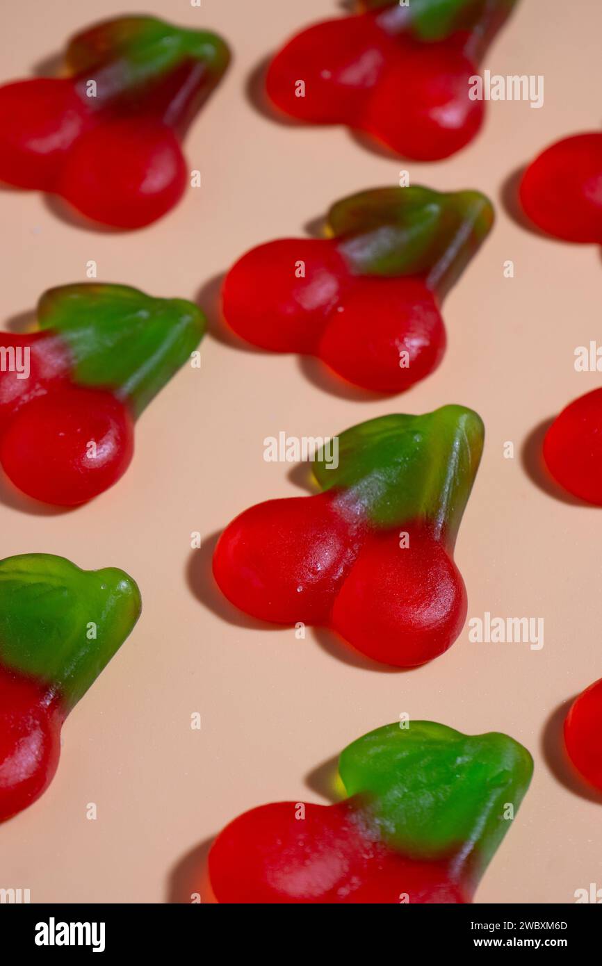 gommes à la cerise végétaliennes posées dans une disposition de grille sur une surface orange pastel avec une lumière dure. vue diagonale de 45 degrés Banque D'Images