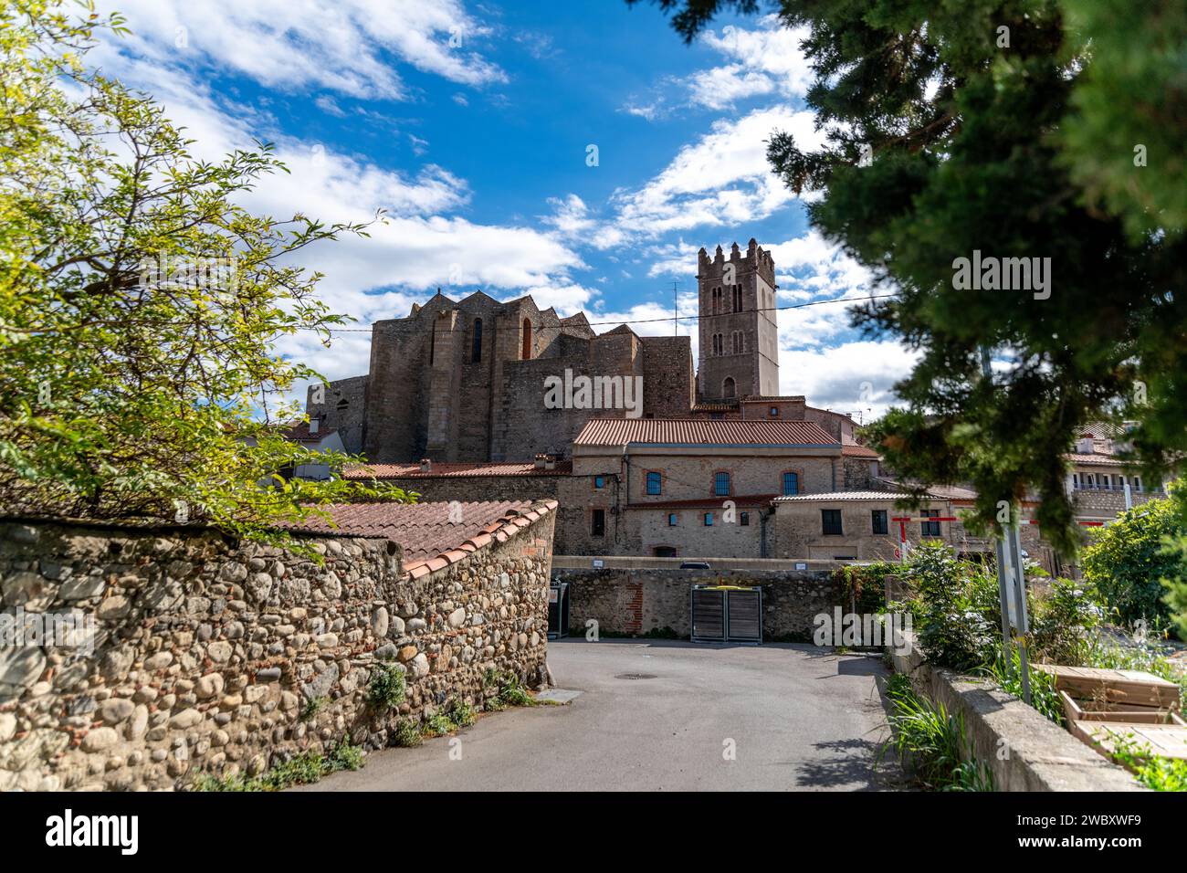 Vue sur l'église d'Ille sur tét depuis un sentier bordé à gauche par un immeuble ancien plat et à droite par un mur. Vous pouvez également voir d'autres vieux buil Banque D'Images