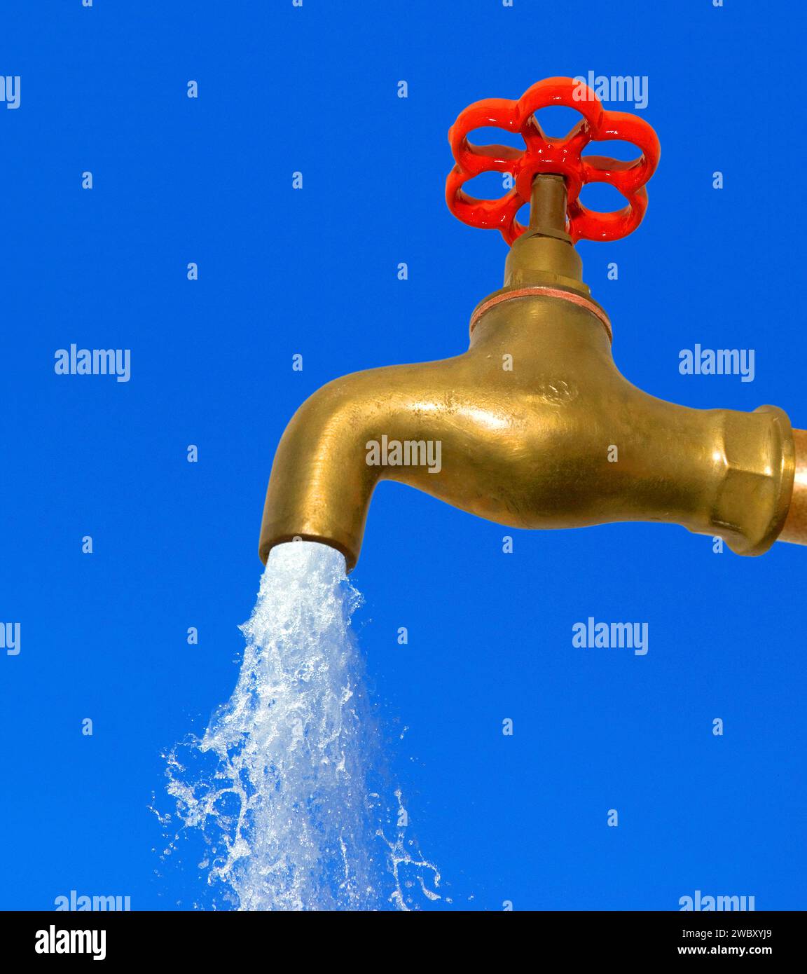 gros plan d'un robinet d'eau en laiton doré avec poignée rouge, l'eau s'écoulant de lui Banque D'Images