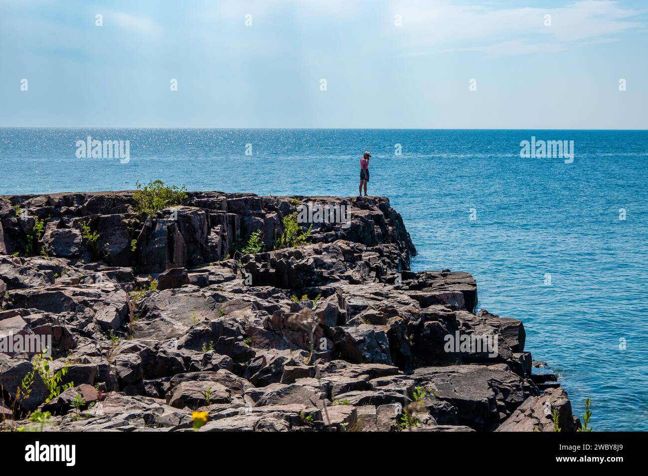 Personne méconnaissable debout seul sur la rive nord rocheuse du magnifique lac supérieur dans le Minnesota. Banque D'Images