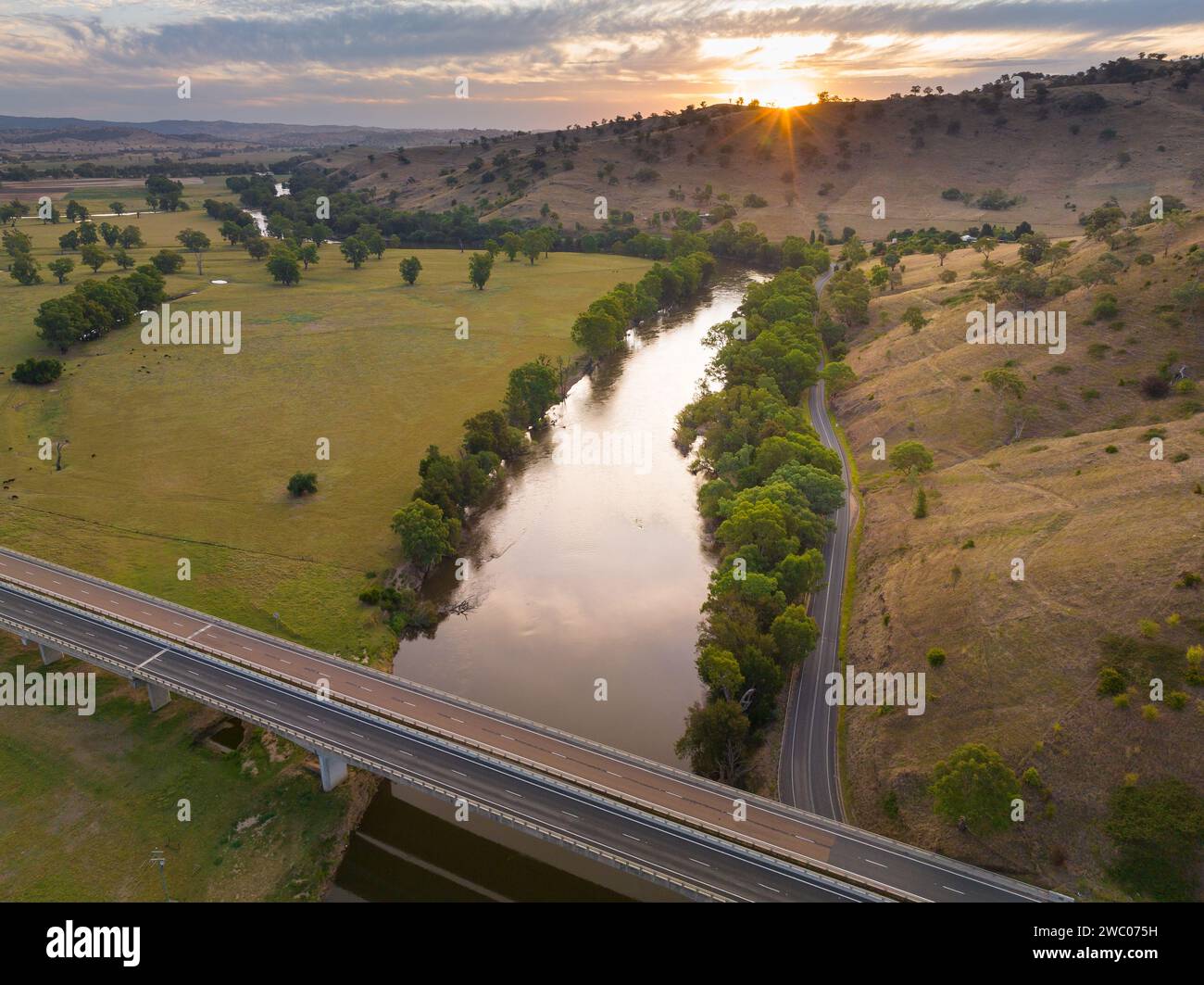 Vue aérienne du coucher de soleil sur les collines entourant une rivière qui coule à travers les terres agricoles à Gundagai en Nouvelle-Galles du Sud, Australie Banque D'Images