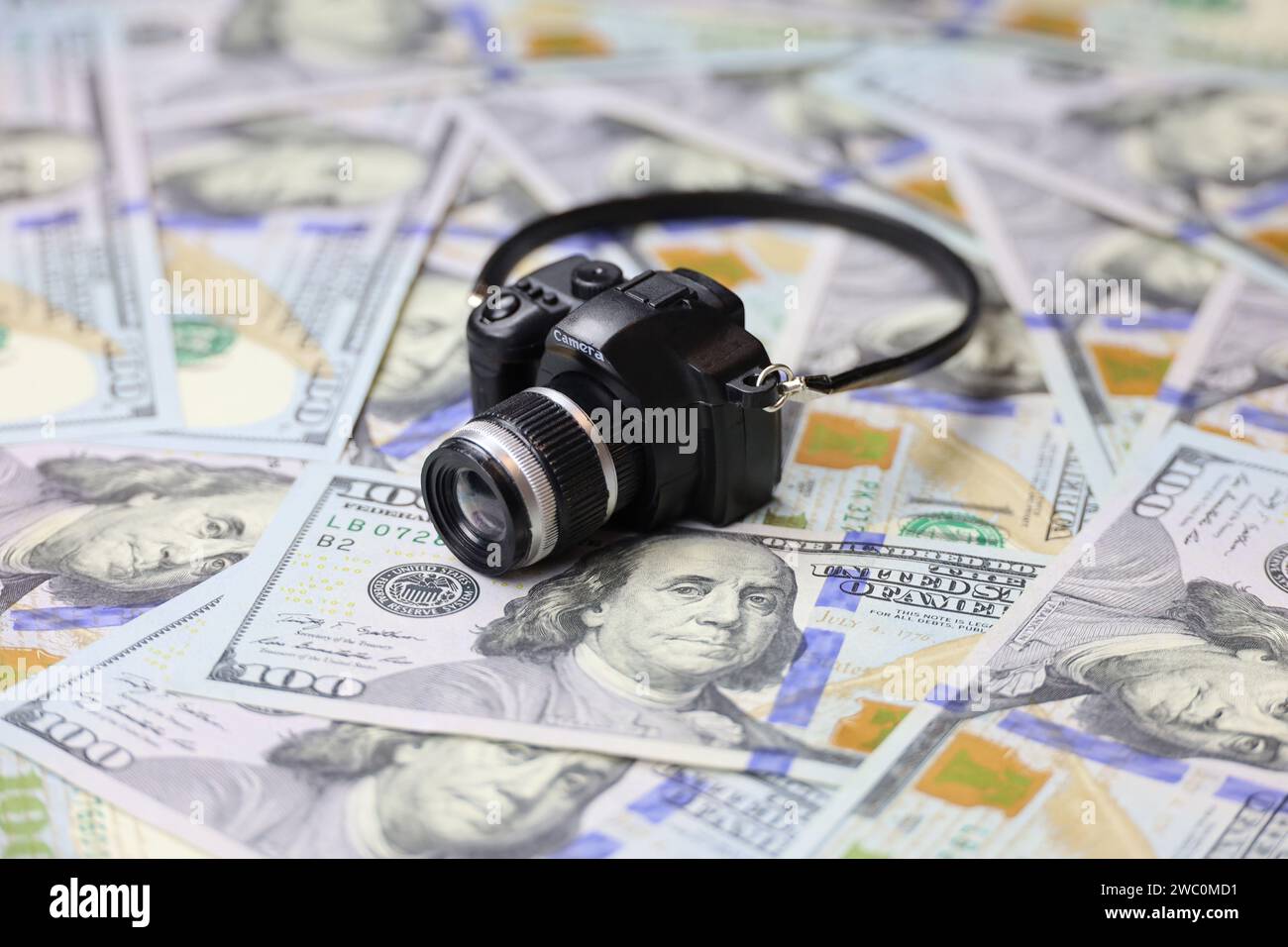Modèle de caméra sur des billets de banque en dollars américains. Concept de revenus de photographe, industrie de la photo Banque D'Images