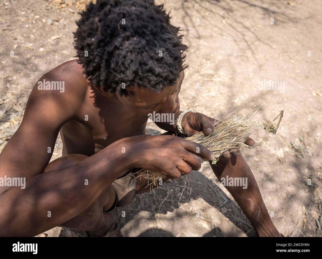 Un San Bushman souffle sur les braises pour tenter de déclencher une flamme en Namibie Banque D'Images