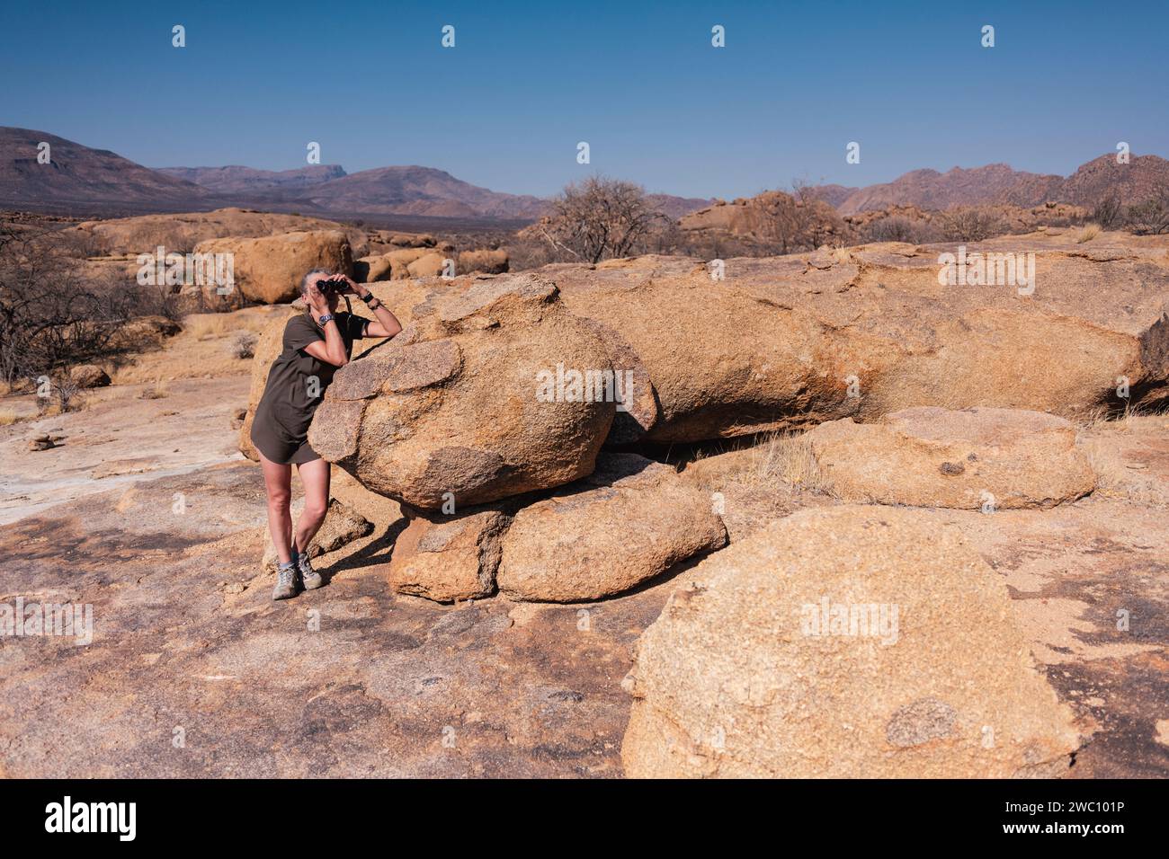 Une femme regarde à travers une paire de jumelles dans la région d'Erongo en Namibie Banque D'Images