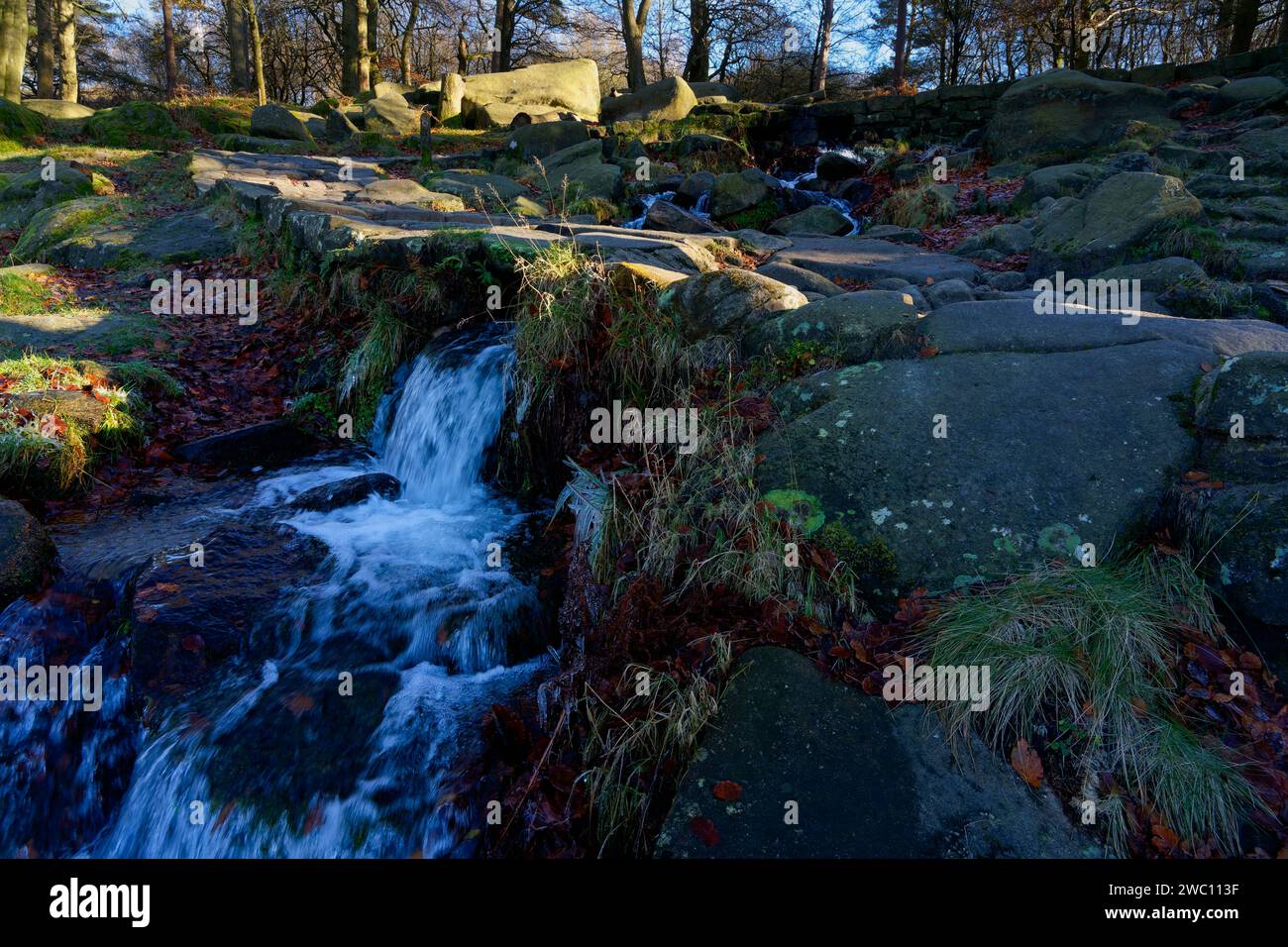 Dans Padley gorge dans le Derbyshire Burbage Brook cascade en descente, au-dessus des roches de pierre de taille et sous un petit pont de pierre. Banque D'Images