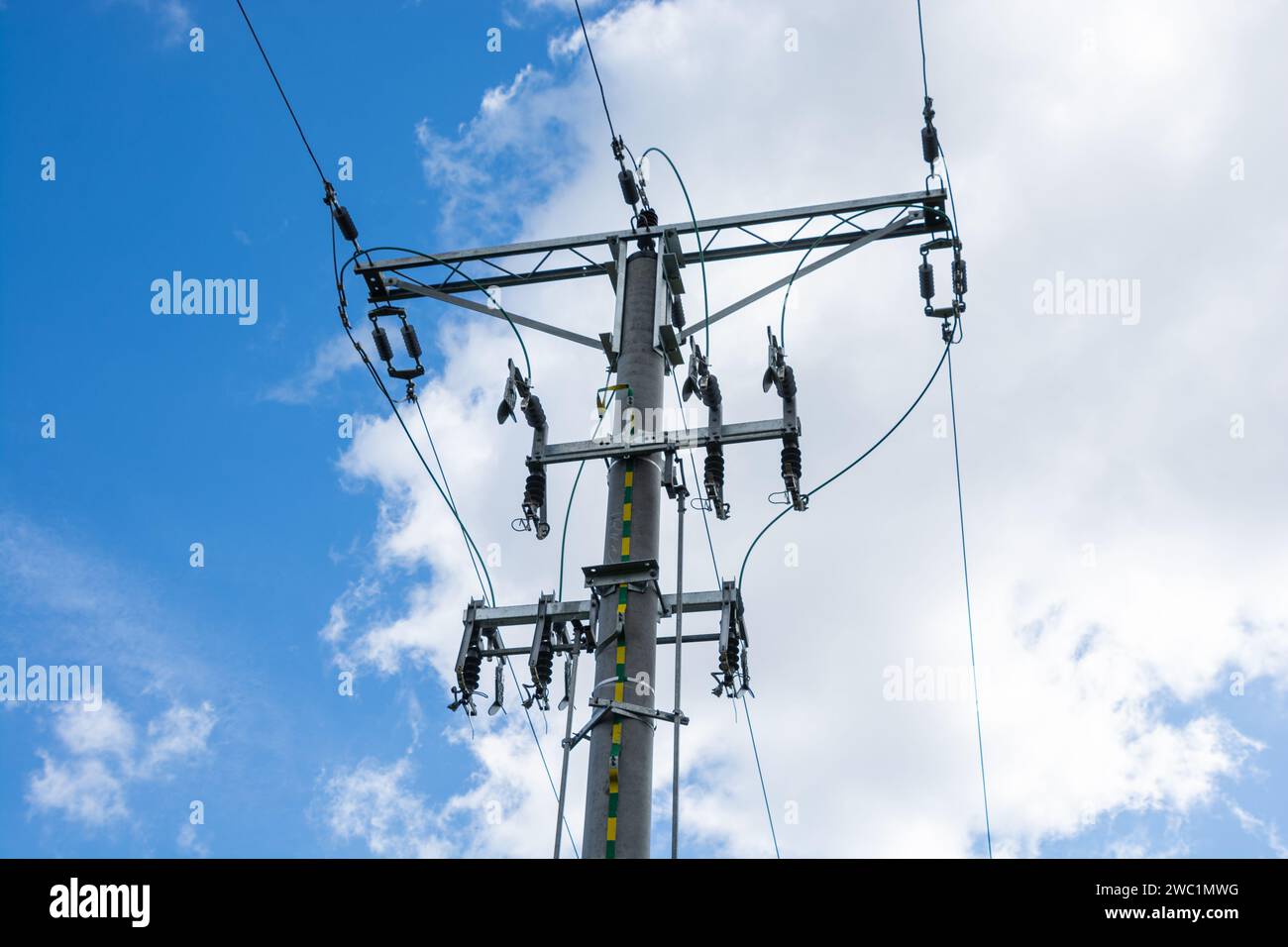 ligne aérienne à haute tension, poteau avec isolateurs et sectionneurs, nuages blancs dans le ciel bleu Banque D'Images