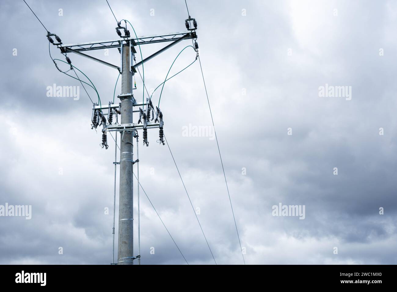 ligne aérienne à haute tension, poteau avec isolateurs et sectionneurs, nuages sombres en arrière-plan Banque D'Images