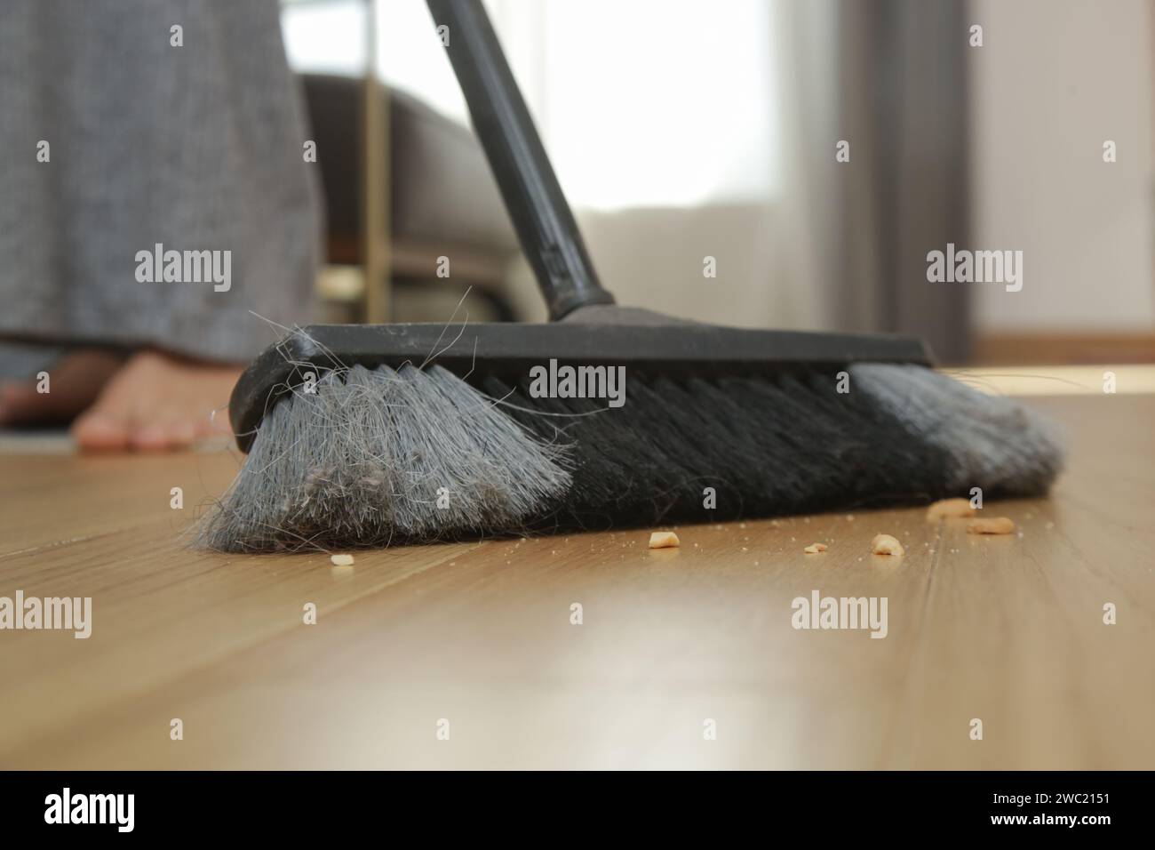 Nettoyage de la maison. Gros plan d'une femme faisant des travaux ménagers, tenant un balai et balayant le sol Banque D'Images