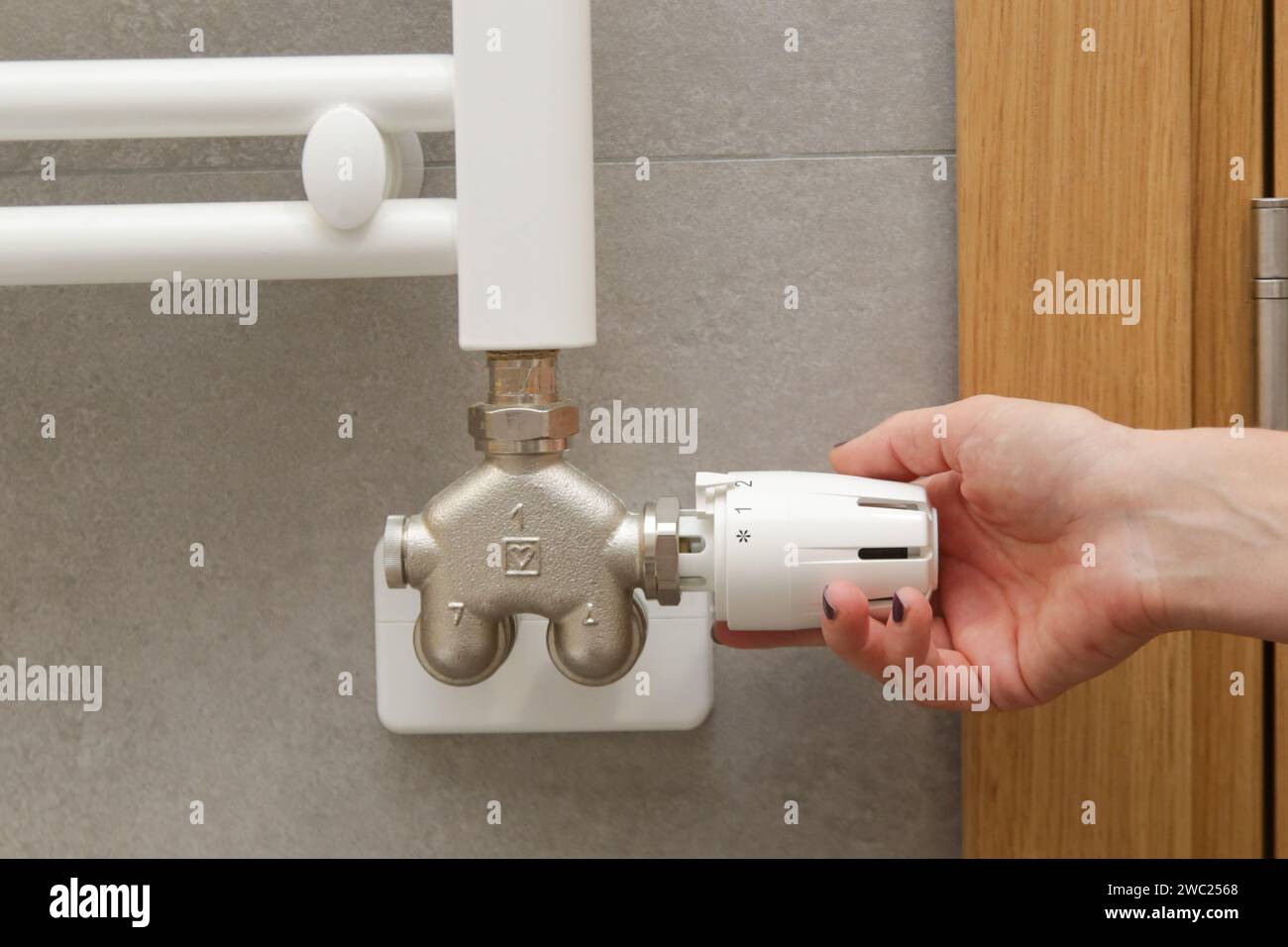 Réglage manuel de la soupape thermostatique du radiateur par une femme, commande du système de chauffage central Banque D'Images