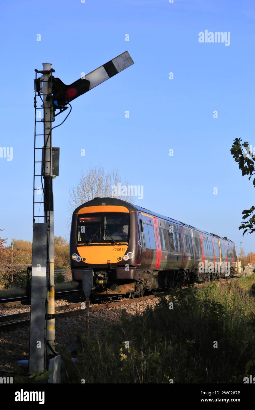 170618 train C2C passant un signal sémaphore, à Whittlesey Town, Fenland, Cambridgeshire, Angleterre Banque D'Images