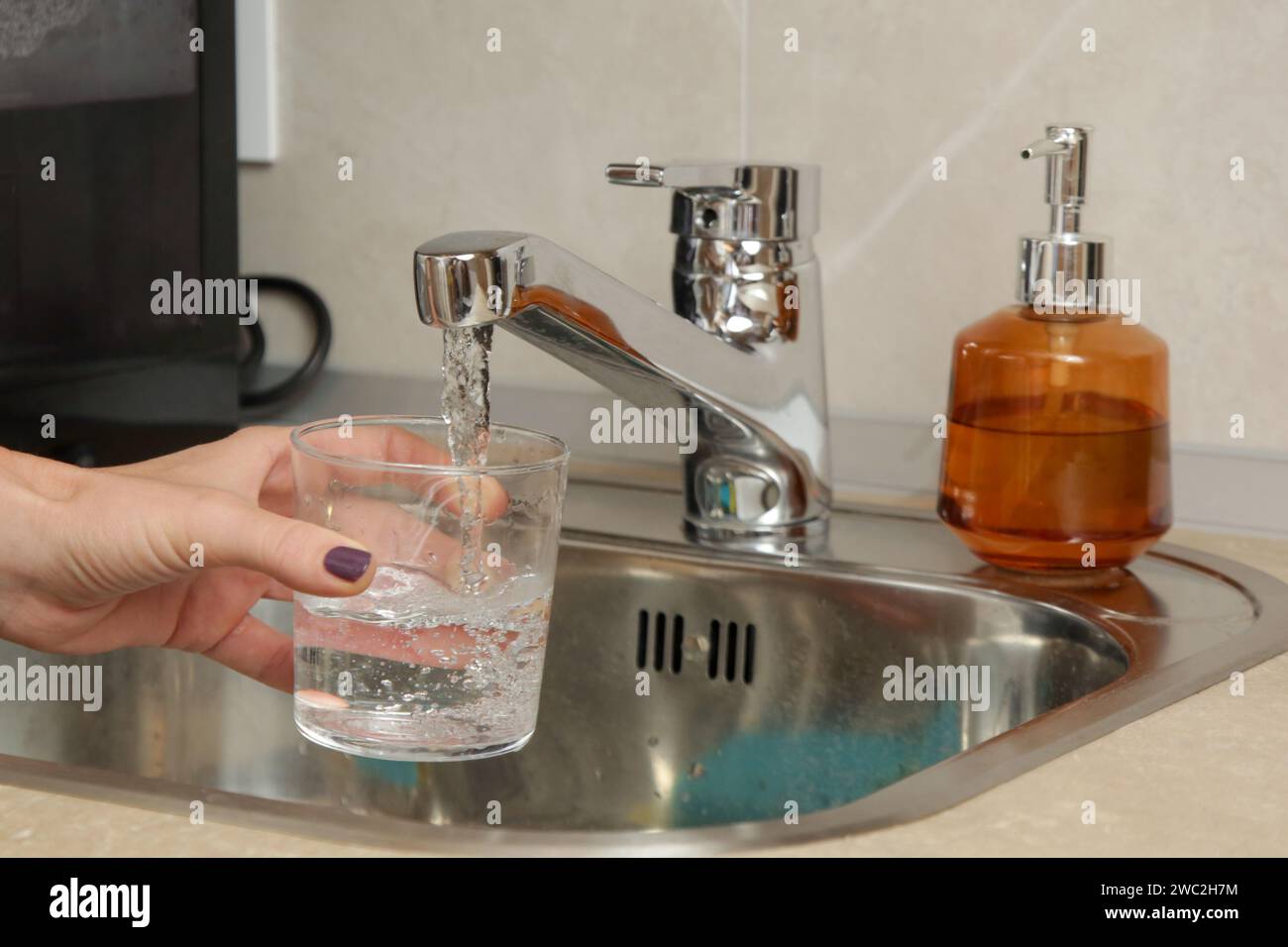 Remplir un verre avec de l'eau potable fraîche du robinet de cuisine Banque D'Images