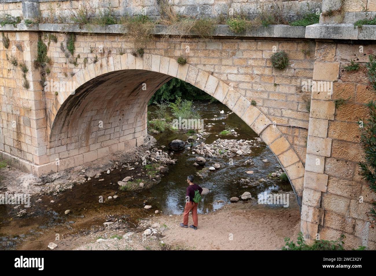 Un visiteur regarde la rivière Arlanza sous le pont médiéval de San Pablo dans le village de Covarrubias Castille et León, Espagne. Banque D'Images