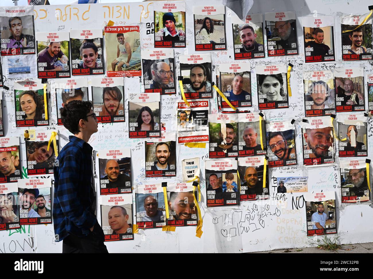 Tel Aviv, Israël. 13 janvier 2024. Un garçon passe devant un mur avec des photos d’Israéliens toujours retenus en otage à Gaza par le Hamas sur la place des otages à tel Aviv le samedi 13 janvier 2024. Le 14 janvier, Israël marquera cent jours depuis le massacre du Hamas sur Israël et appellera à la libération des 136 otages encore détenus par le Hamas à Gaza. Photo de Debbie Hill/ crédit : UPI/Alamy Live News Banque D'Images Tel Aviv, Israël. 13 janvier 2024. Un garçon passe devant un mur avec des photos d’Israéliens toujours retenus en otage à Gaza par le Hamas sur la place des otages à tel Aviv le samedi 13 janvier 2024. Le 14 janvier, Israël marquera cent jours depuis le massacre du Hamas sur Israël et appellera à la libération des 136 otages encore détenus par le Hamas à Gaza. Photo de Debbie Hill/ crédit : UPI/Alamy Live News Banque D'Images