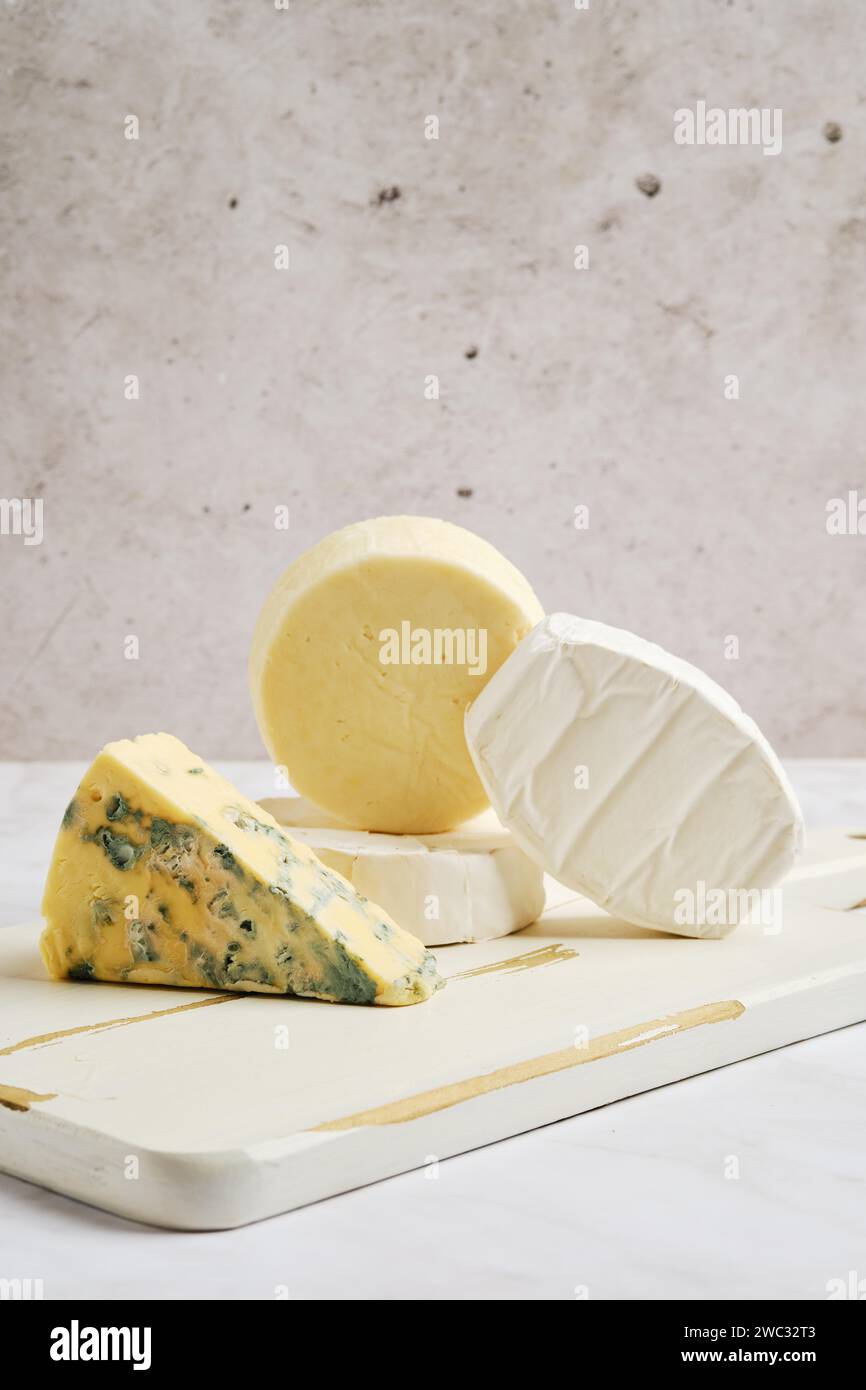 Morceaux de brie, camembert, fromage de chèvre et fromage avec moule bleu sur une planche de service en bois Banque D'Images Morceaux de brie, camembert, fromage de chèvre et fromage avec moule bleu sur une planche de service en bois Banque D'Images