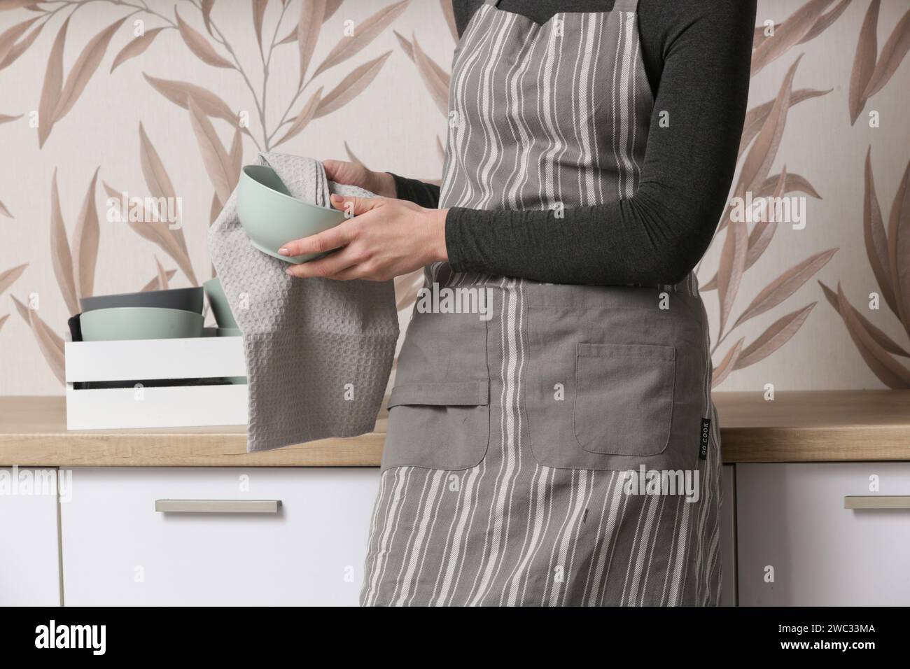 Femme au foyer dans le tablier rangeant la vaisselle dans la cuisine, la vie domestique, l'organisation générale et le concept de désencombrement Banque D'Images