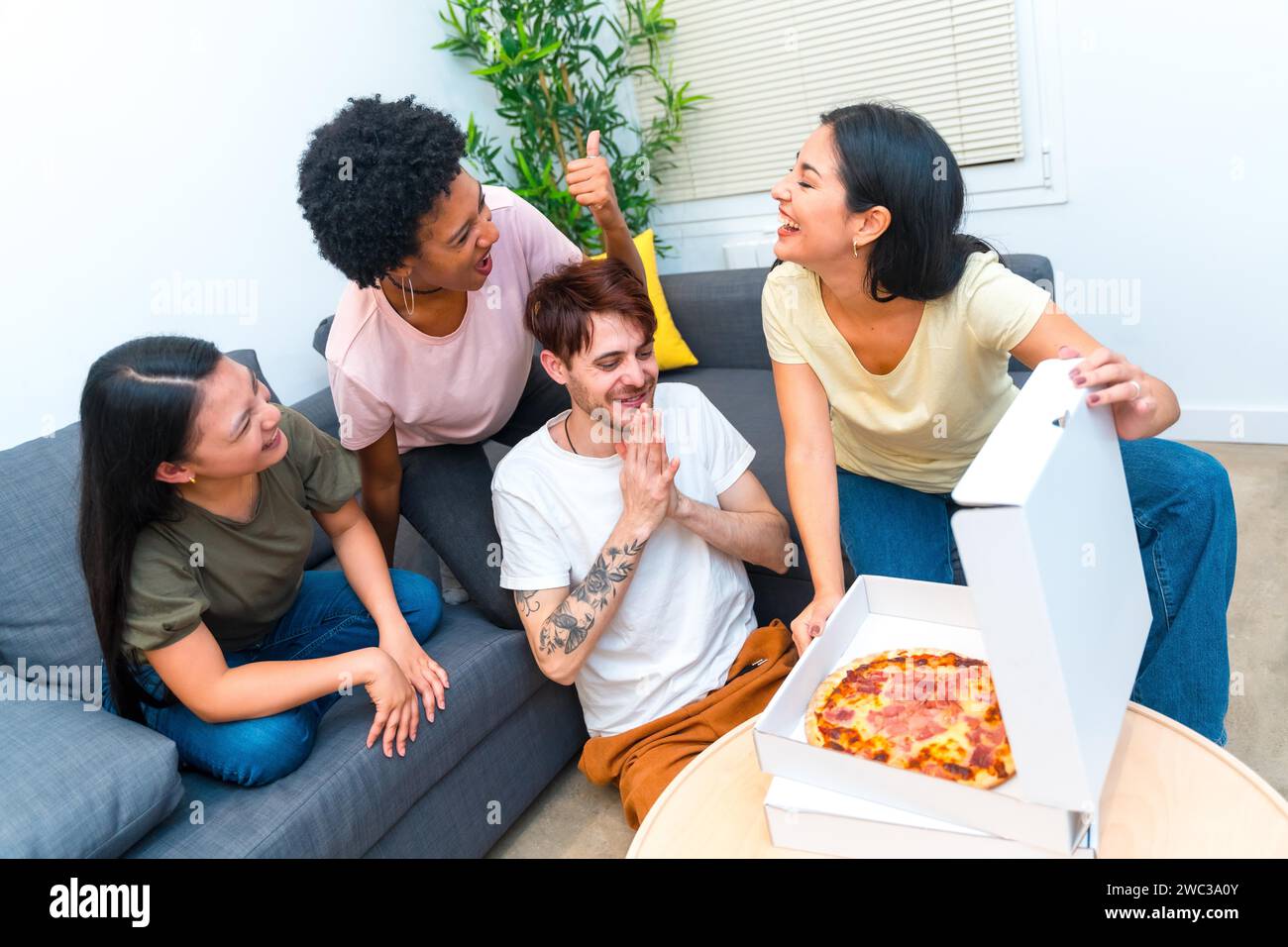 Vue de dessus d'un groupe d'amis affamés multi-ethniques ouvrant une boîte à pizza livrée Banque D'Images