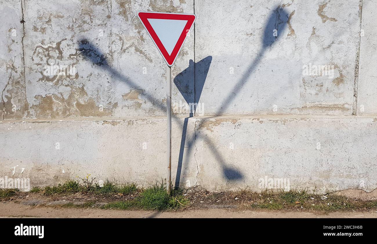 Panneau de signalisation de sortie, pas de zone de passage. Avertissement. Triangle inversé - forme de diamant avec des couleurs rouges et blanches. Ombres abstraites sur le fond du mur. Banque D'Images