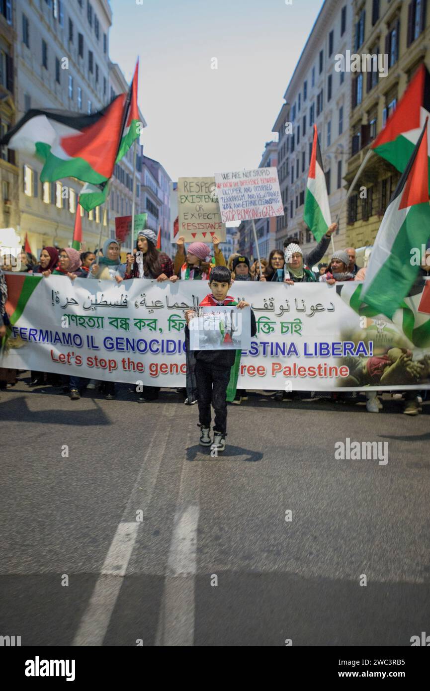Rome, Italie. 13 janvier 2024. Un enfant à la tête de la procession avec un morceau de papier où il y a une main aux couleurs du drapeau palestinien faisant le signe de la victoire et un petit morceau de papier avec les mots ''sauver gaza'' pendant le rassemblement de solidarité palestinien à Rome. Des centaines de personnes ont participé à la manifestation organisée par le mouvement des étudiants palestiniens en Italie, l'Union démocratique arabe palestinienne (UDAP) et l'Association des Palestiniens en Italie (API) pour soutenir le peuple palestinien et sensibiliser l'opinion publique au génocide perpétré par le gouvernement israélien Banque D'Images