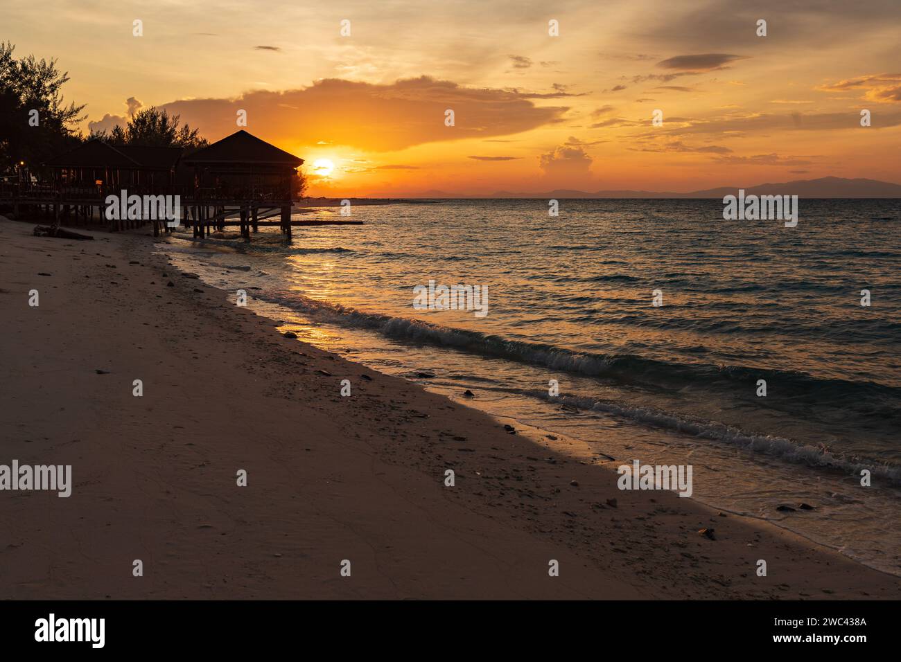 Sunrise silhouettes un quai et un belvédère sur une belle plage tropicale Banque D'Images