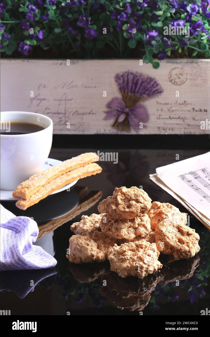 Une tasse de café chaud le matin avec des biscuits macaronés et des craquelins de sucre anis avec de la musique et des fleurs. Banque D'Images