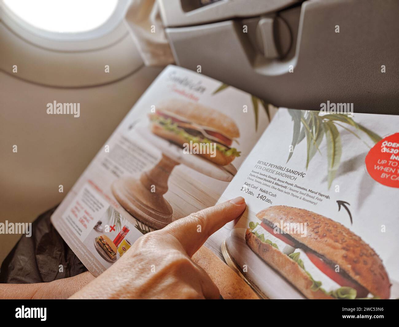 Ankara-Turquie : octobre 15 :2023 : Femme passager regardant le menu à bord et commandant un sandwich pendant un vol dans l'avion. Banque D'Images