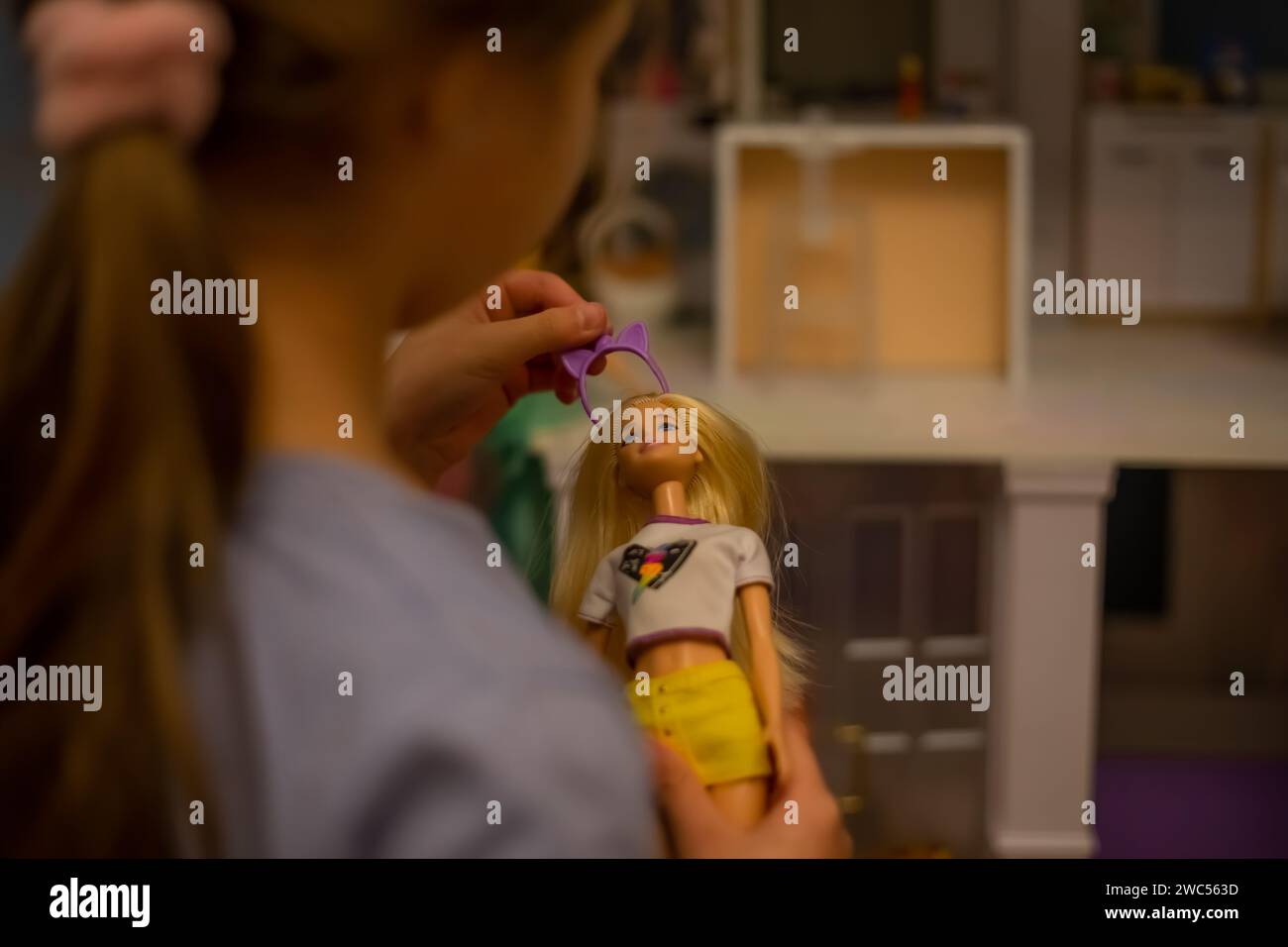 Une fille joue avec une poupée. Drôle charmant enfant s'amuse dans la chambre des enfants. Banque D'Images