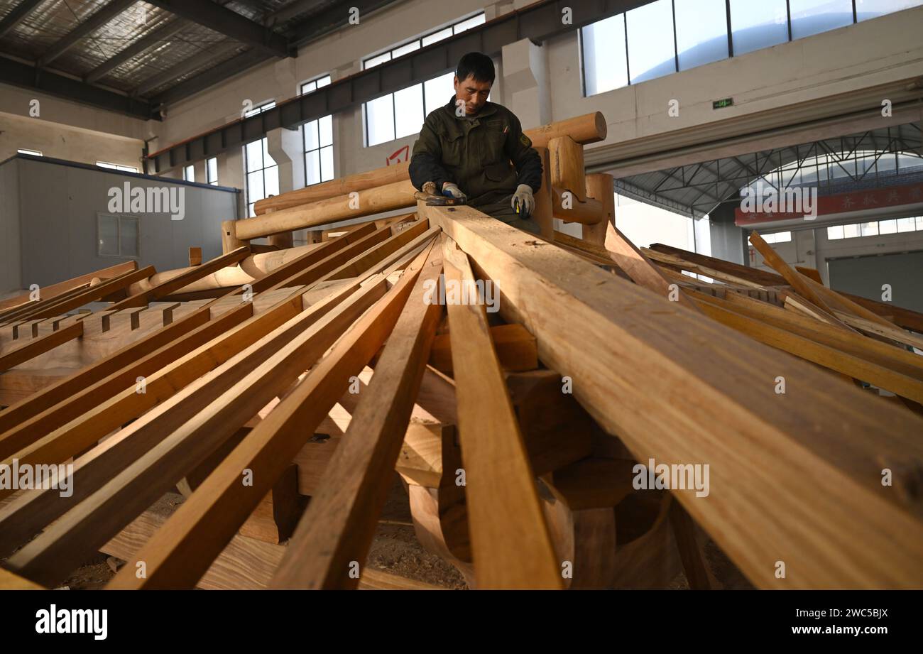 (240114) -- HUANGSHAN, 14 janv. 2024 (Xinhua) -- Un membre du personnel installe une structure en bois pour des bâtiments anciens de style Huizhou dans la ville de Huangshan, dans la province de l'Anhui dans l'est de la Chine, le 11 janvier 2024. Huangshan a stimulé le service de construction spécialisé dans les bâtiments antiques de style Huizhou d'une manière innovante, attirant de nombreuses entreprises et talents à s'engager dans l'industrie. À ce jour, il y a 254 entreprises et plus de 14 000 artisans impliqués, qui se spécialisent dans la construction de bâtiments anciens, la rénovation de bâtiments anciens et la préparation de matériaux et de composants pour ces bâtiments. (Xinhua/Zhou Mu) Banque D'Images
