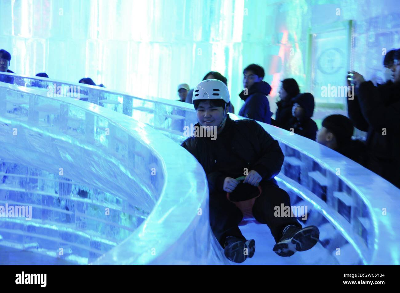 Province de Gangwon, Corée du Sud. 13 janvier 2024. Un touriste profite d’une glissade de glace réalisée par les sculpteurs de glace Harbin lors du festival de glace Hwacheon Sancheoneo dans la province de Gangwon, Corée du Sud, le 13 janvier 2024. Capitale de la province la plus septentrionale de la Chine, Heilongjiang, Harbin est réputée pour être le « joyau de la glace et de la neige » du pays. Cette année, les sculpteurs de glace de Harbin ont été invités à créer des sculptures de glace pour le festival de glace de Hwacheon Sancheoneo, l'un des festivals d'hiver sud-coréens les plus populaires. Crédit : Yang Chang/Xinhua/Alamy Live News Banque D'Images