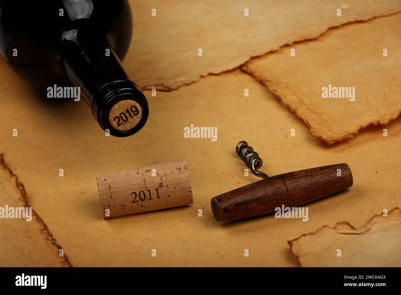 Gros plan sur une bouteille de vin rouge non ouverte avec liège et ouvre-fenêtre rétro avec poignée en bois sur fond de papier brun vintage avec espace de copie, an haut Banque D'Images