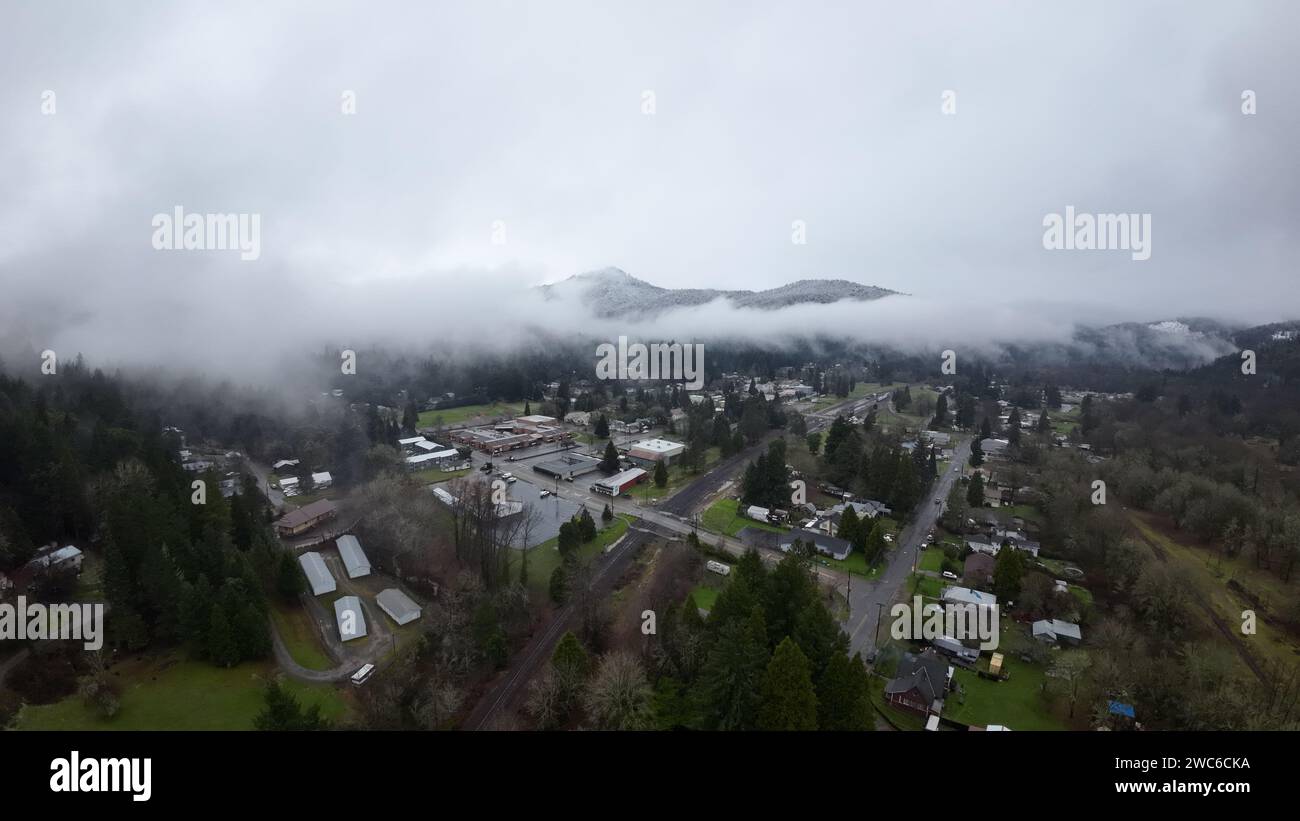 Une vue enchanteresse sur une ville pittoresque nichée au milieu de montagnes majestueuses, tandis que la brume éthérée descend délicatement des sommets Banque D'Images