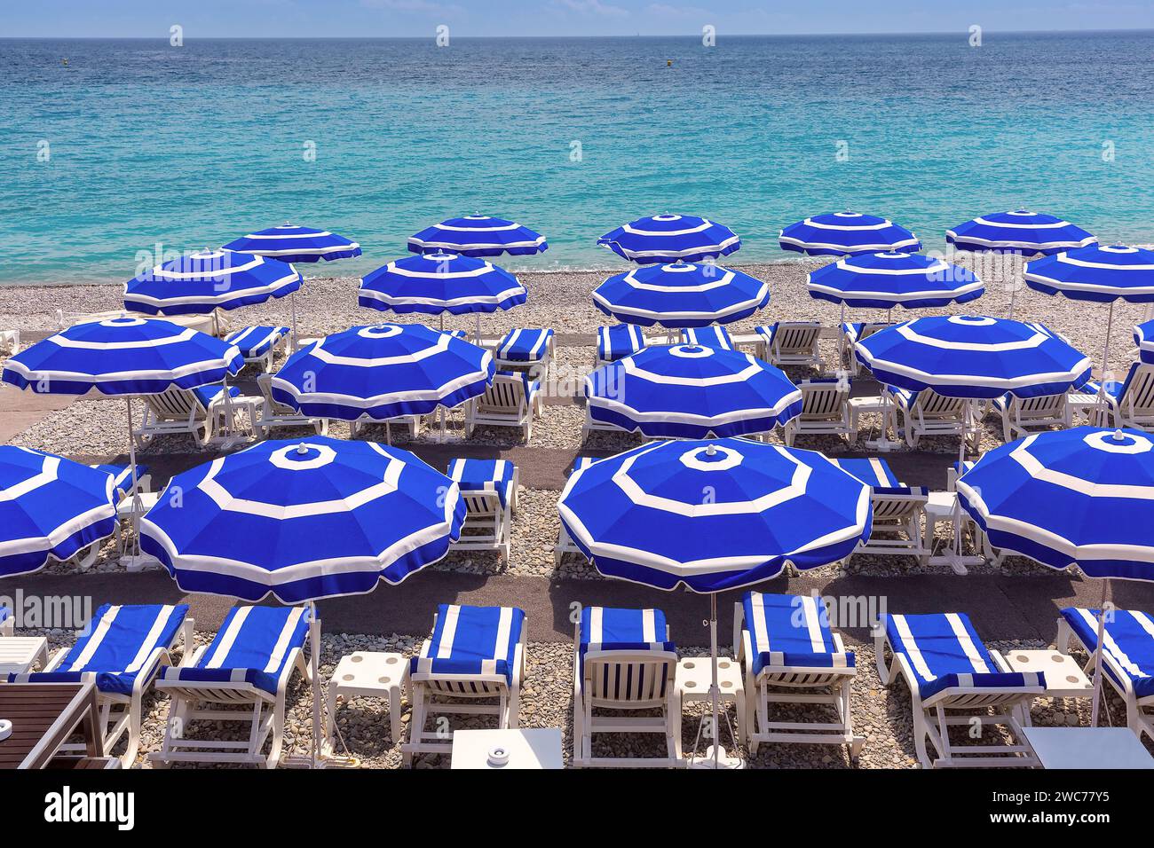 Parasols sur la plage de Nice en journée ensoleillée d'été avec ciel bleu, Nice, Côte d'Azur, France Banque D'Images