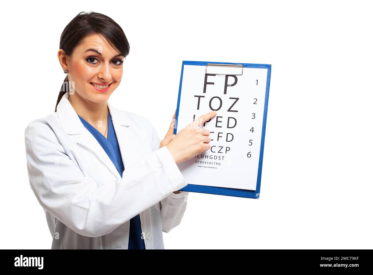 Femme souriante en blouse de laboratoire pointant vers le tableau de test oculaire, isolé sur blanc Banque D'Images