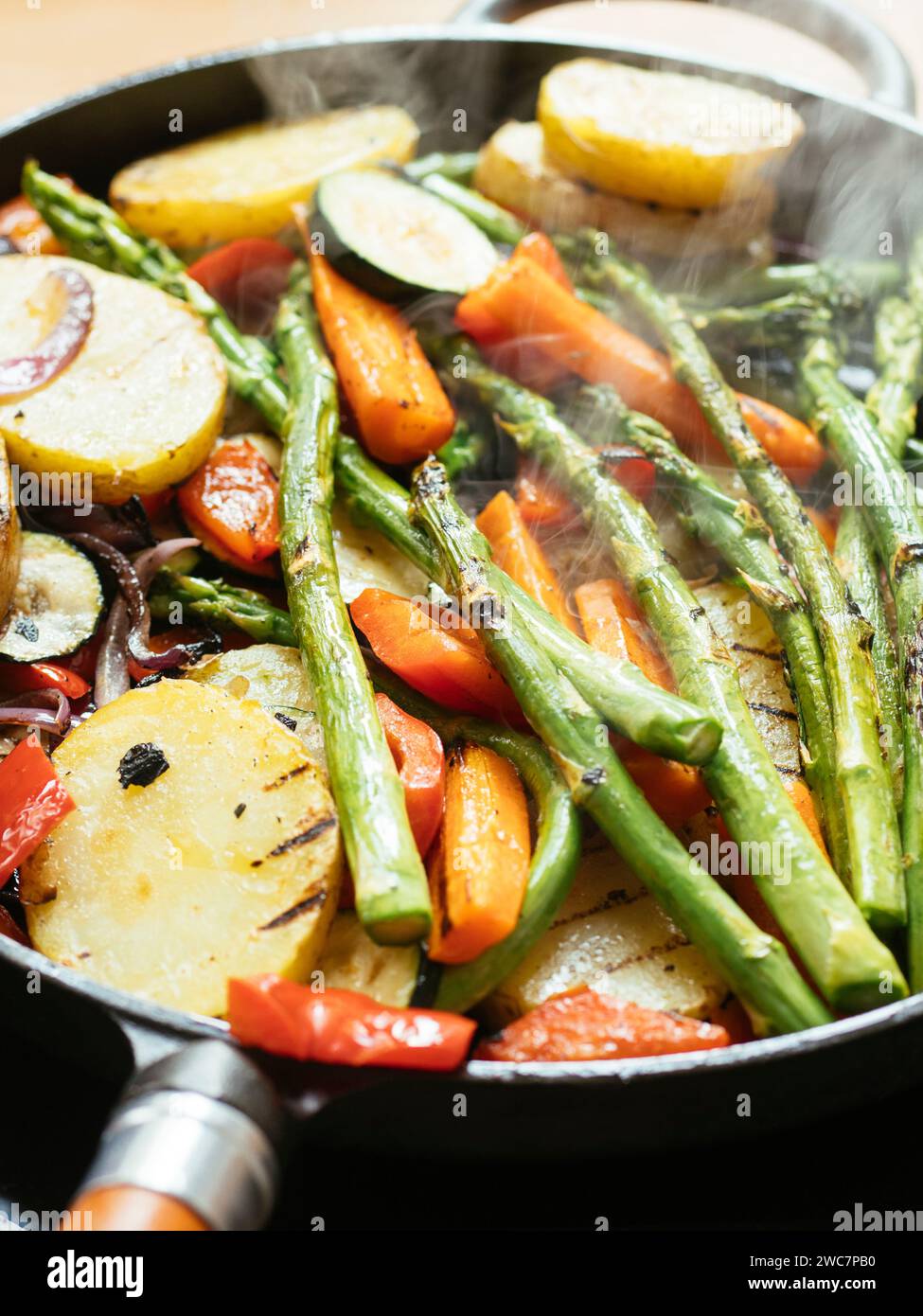 Un mélange de légumes (asperges, courgettes, poivrons, carottes, oignons, pommes de terre) d'être grillés dans une poêle en fonte. Banque D'Images