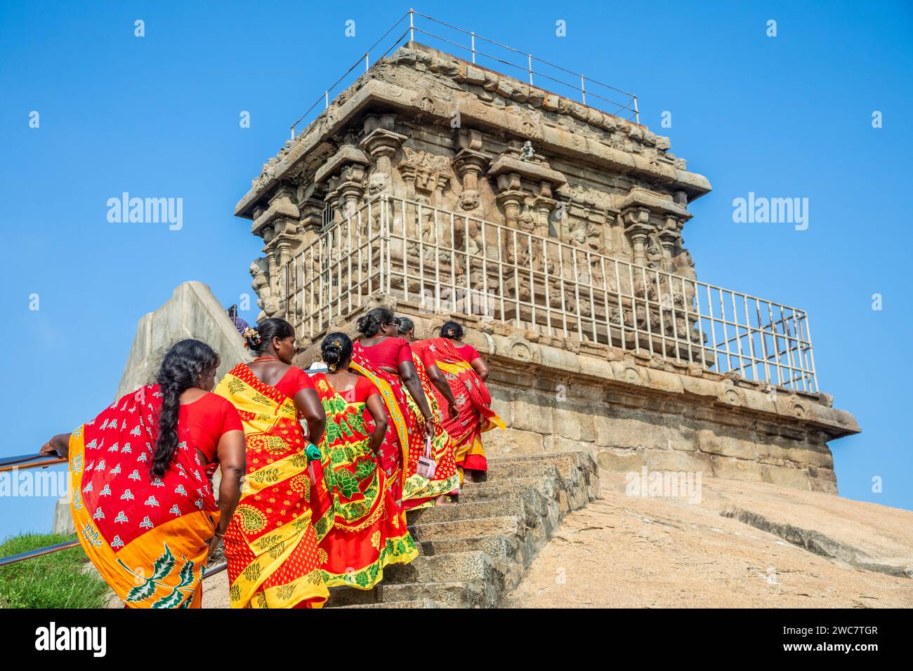 Groupe de pèlerines vêtues de sarees rouges et jaunes colorés sur le chemin du temple Olakkannesvara, Mahabalipuram, région de Tondaimandalam, Tamil Nadu Banque D'Images