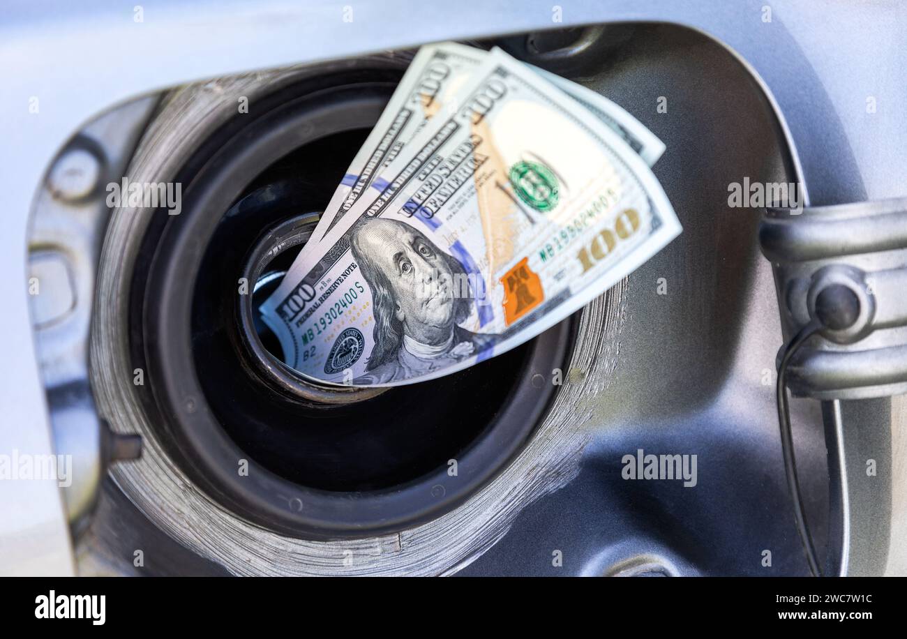 Billets de dollars américains dans le réservoir d'essence d'un véhicule. Photo conceptuelle de la hausse du prix du carburant. Économie de carburant. Coût élevé du carburant Banque D'Images