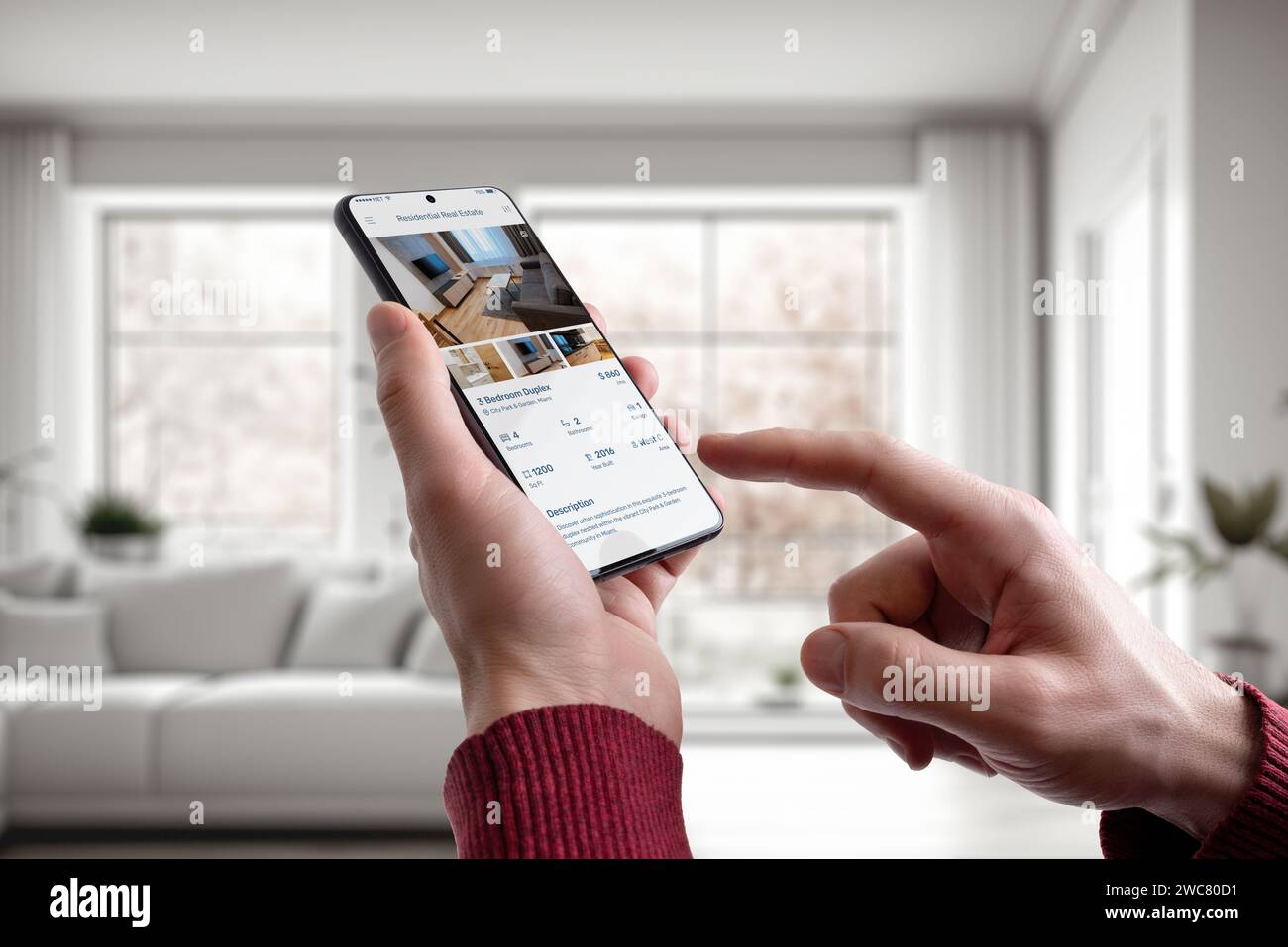 Guy à la maison en utilisant un smartphone avec une application immobilière résidentielle. La technologie moderne fusionne parfaitement avec le confort de la maison pour une propriété pratique Banque D'Images