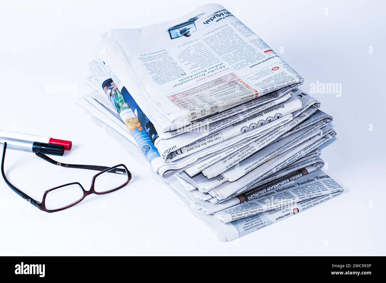 piles de journaux qui doivent être lus pour obtenir des informations sur les affaires et les nouvelles financières, plus papeterie et lunettes sur la table Banque D'Images