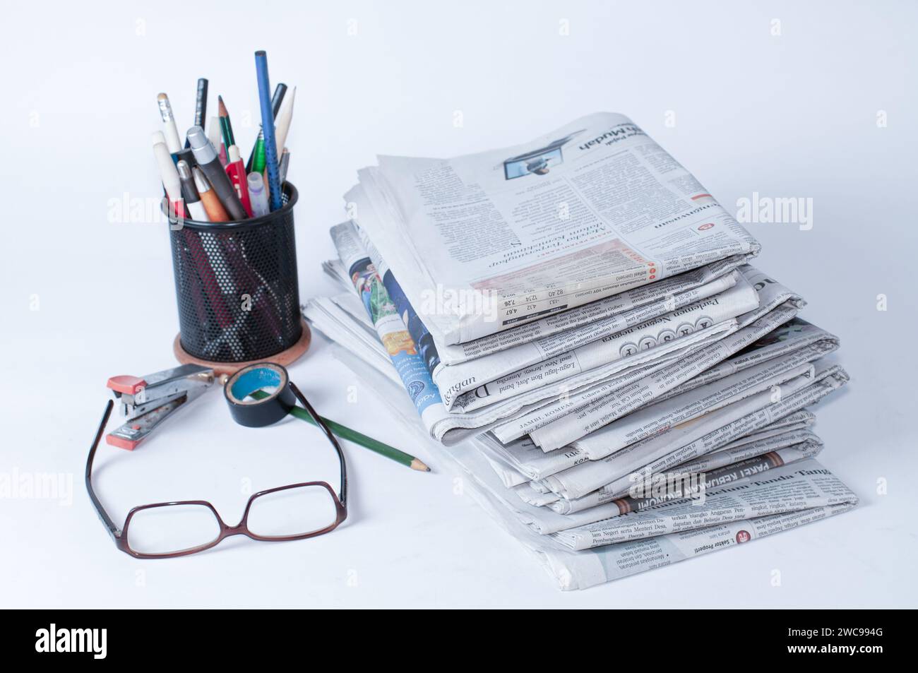 piles de journaux qui doivent être lus pour obtenir des informations sur les affaires et les nouvelles financières, plus papeterie et lunettes sur la table Banque D'Images