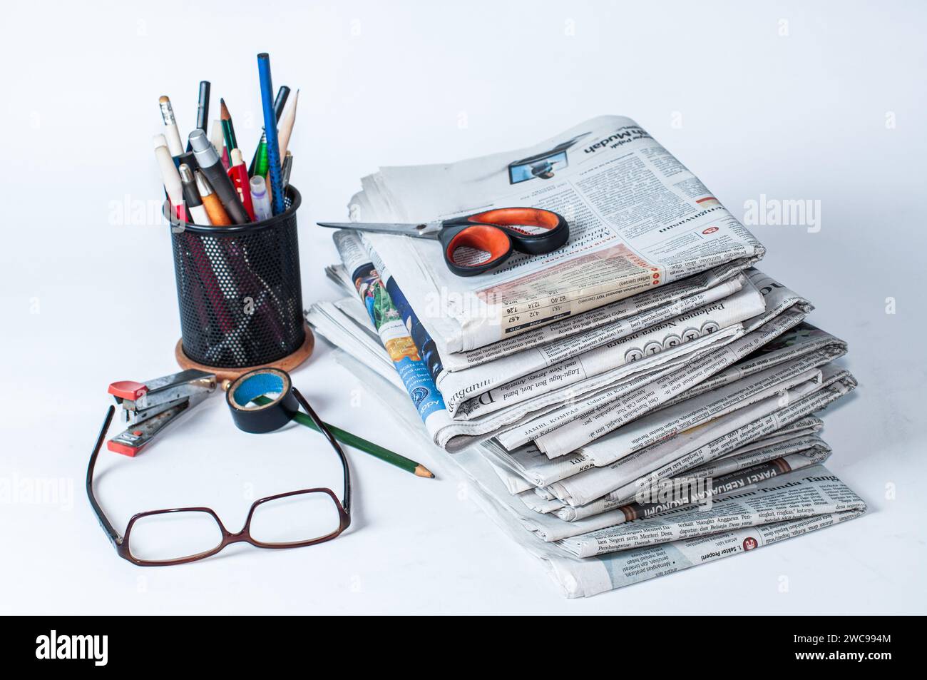piles de journaux qui doivent être lus pour obtenir des informations sur les affaires et les nouvelles financières, plus papeterie et lunettes sur la table Banque D'Images