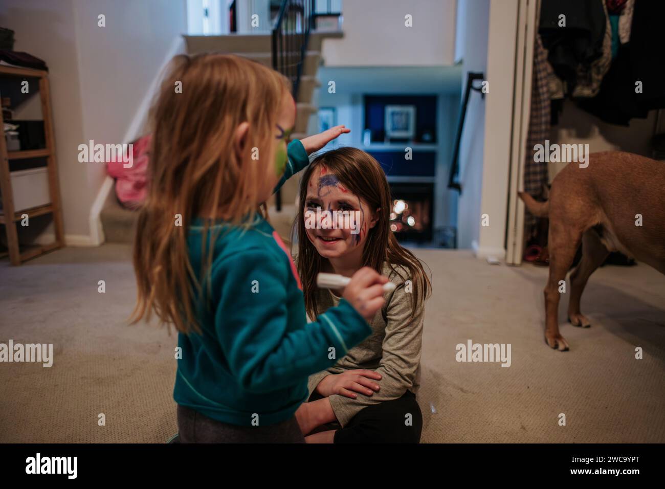 Jeunes filles heureuses utilisant de la peinture pour le visage les unes sur les autres Banque D'Images