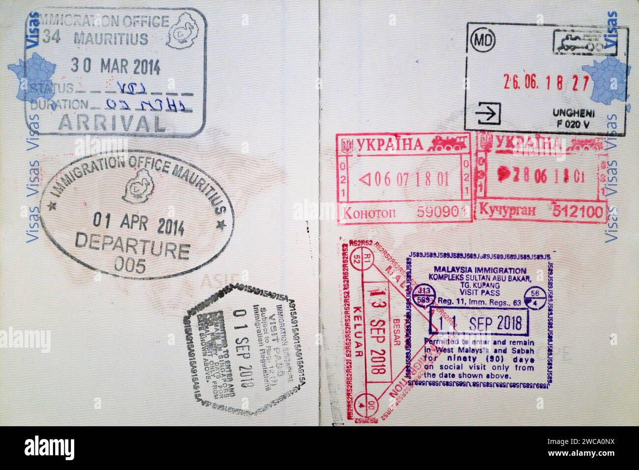 Gros plan sur les doubles pages d'un passeport biométrique français rempli de timbres d'Ukraine, de Moldavie, de Maurice, de Singapour et de Malaisie. Banque D'Images