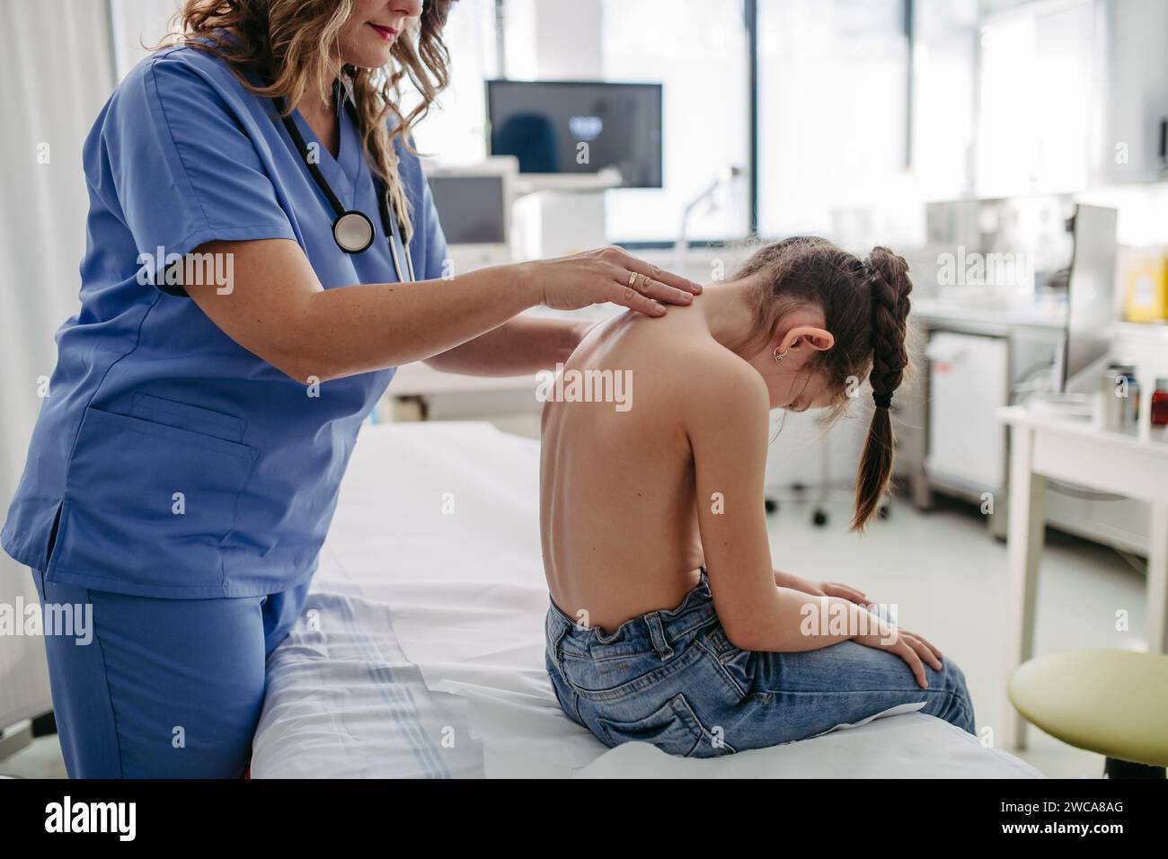 Orthopédiste examine la colonne vertébrale, la posture et les déformations spinales de la petite fille. Jeune fille en visite chez un pédiatre pour un examen préventif annuel. Concept de Banque D'Images