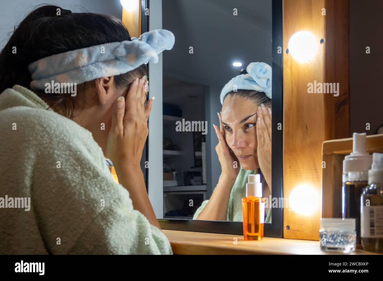 Femme devant le miroir la nuit prenant soin de sa peau. Banque D'Images