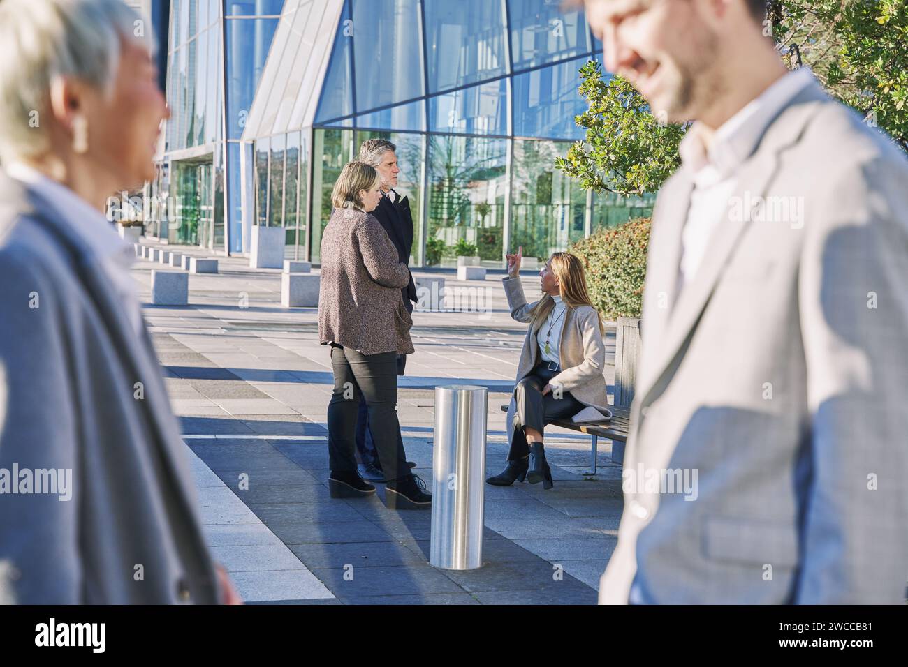 deux jeunes hommes d'affaires ayant rompu, parlant hors de focus au premier plan et un groupe parlant en arrière-plan dans le focus Banque D'Images