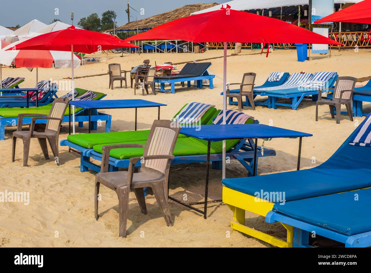 parasols de plage en bois coloré et chaises longues sur la plage de sable de l'océan Banque D'Images
