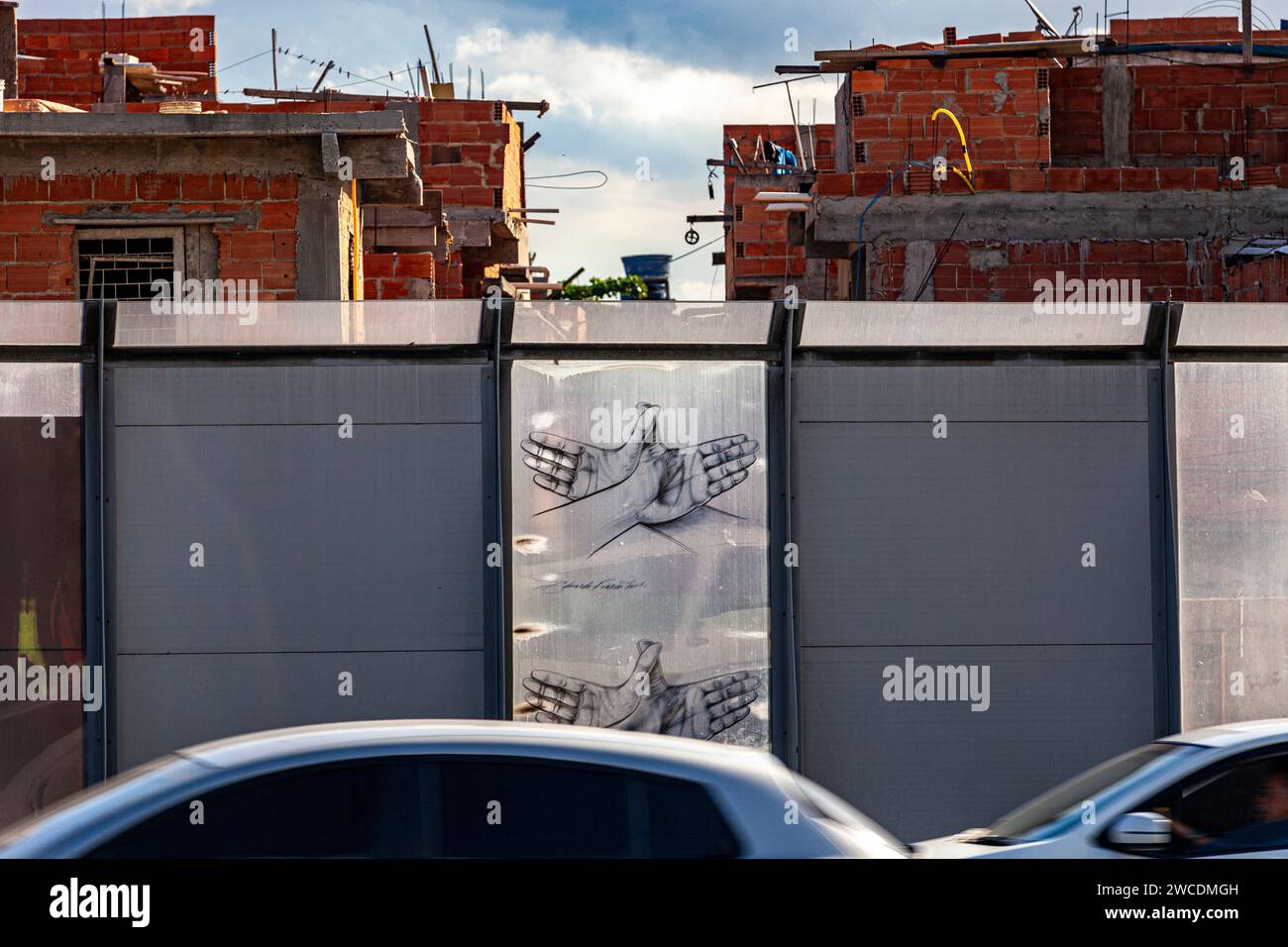 Complexo da Mare, un vaste réseau de favelas qui se trouve le long de la Linha Vermelha ( ligne rouge ), la principale autoroute de l'aéroport international de Rio de Janeiro au centre-ville - la communauté a été clôturée de l'autoroute par d'énormes panneaux Perspex - un haut de 3 mètres, barrière de séparation de 7 km ornée de graffitis- les autorités affirment qu’elle fournit une barrière acoustique, les habitants la décrivent comme un « mur de la honte », une autre façon de cacher les pauvres. Banque D'Images