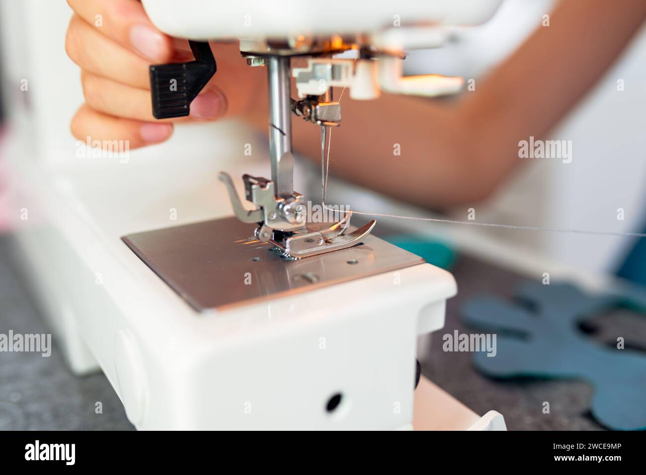 Gros plan de la machine à coudre et de la main de couturière au travail. La fillette coud des vêtements sur la machine à coudre. Ateliers de confection créative pour enfants - conc Banque D'Images