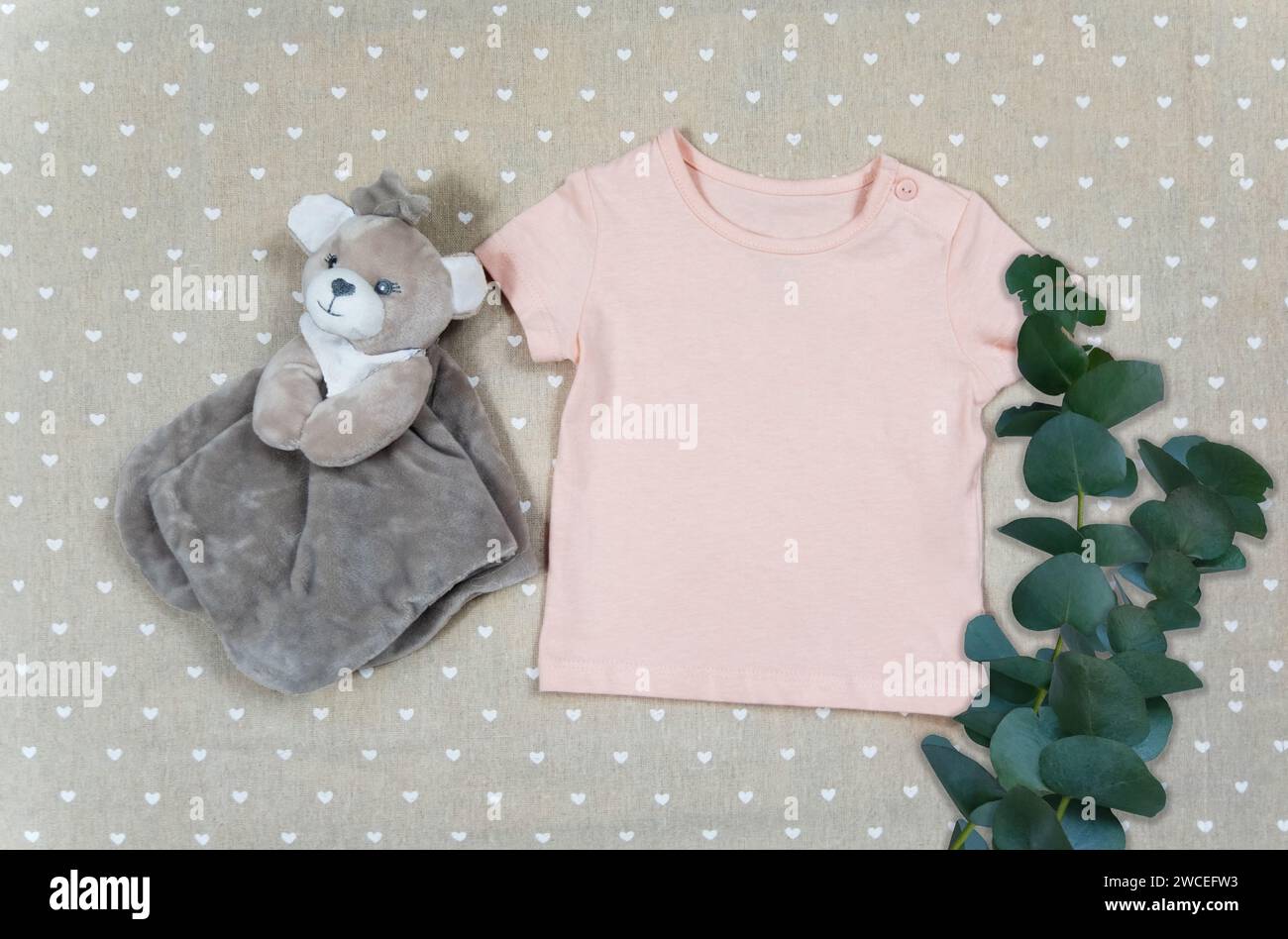 T-shirt enfants avec jouet, eucalyptus vert feuilles branche plante Evergreen vue de dessus gros plan plat minimaliste, maquette simple pour afficher votre art ou produit, fond textile beige, mise au point douce Banque D'Images