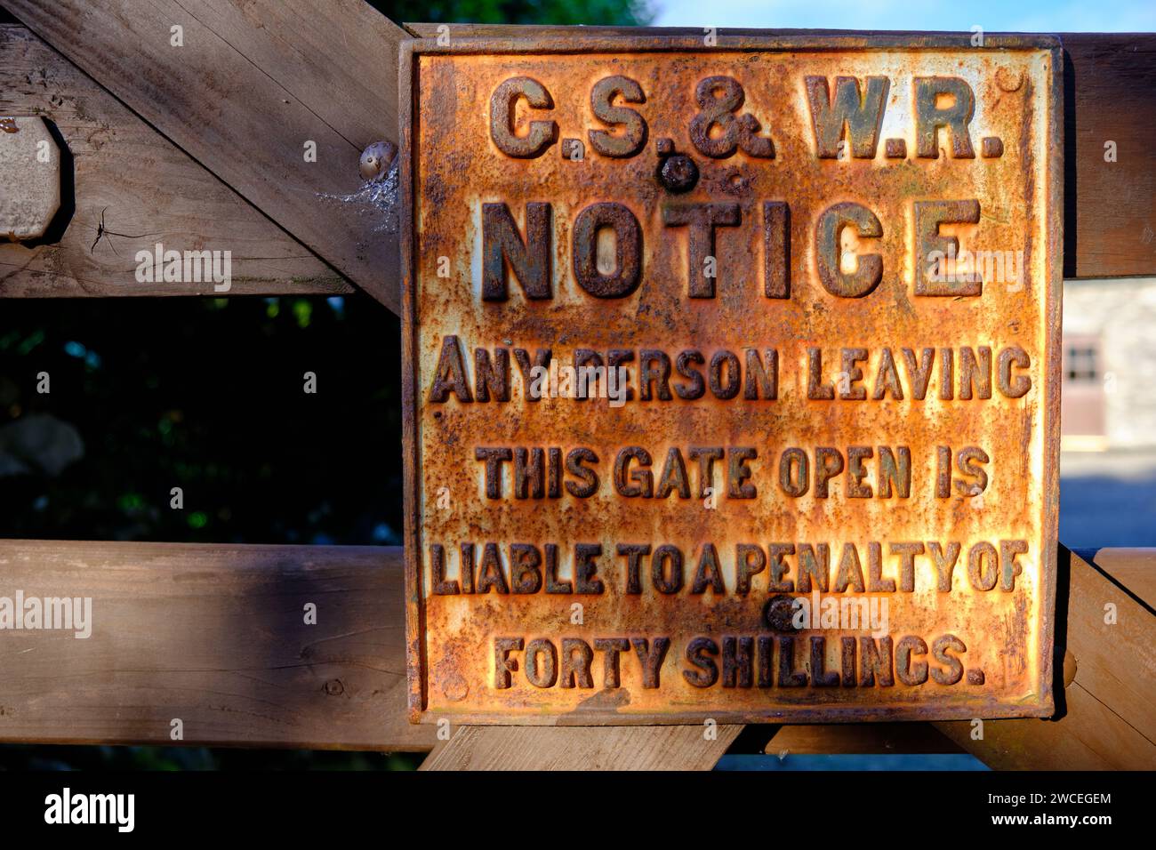Ancien panneau métallique d'avertissement ferroviaire rouillé : « Notez que toute personne laissant cette barrière ouverte est passible d'une pénalité de quarante shillings » Banque D'Images
