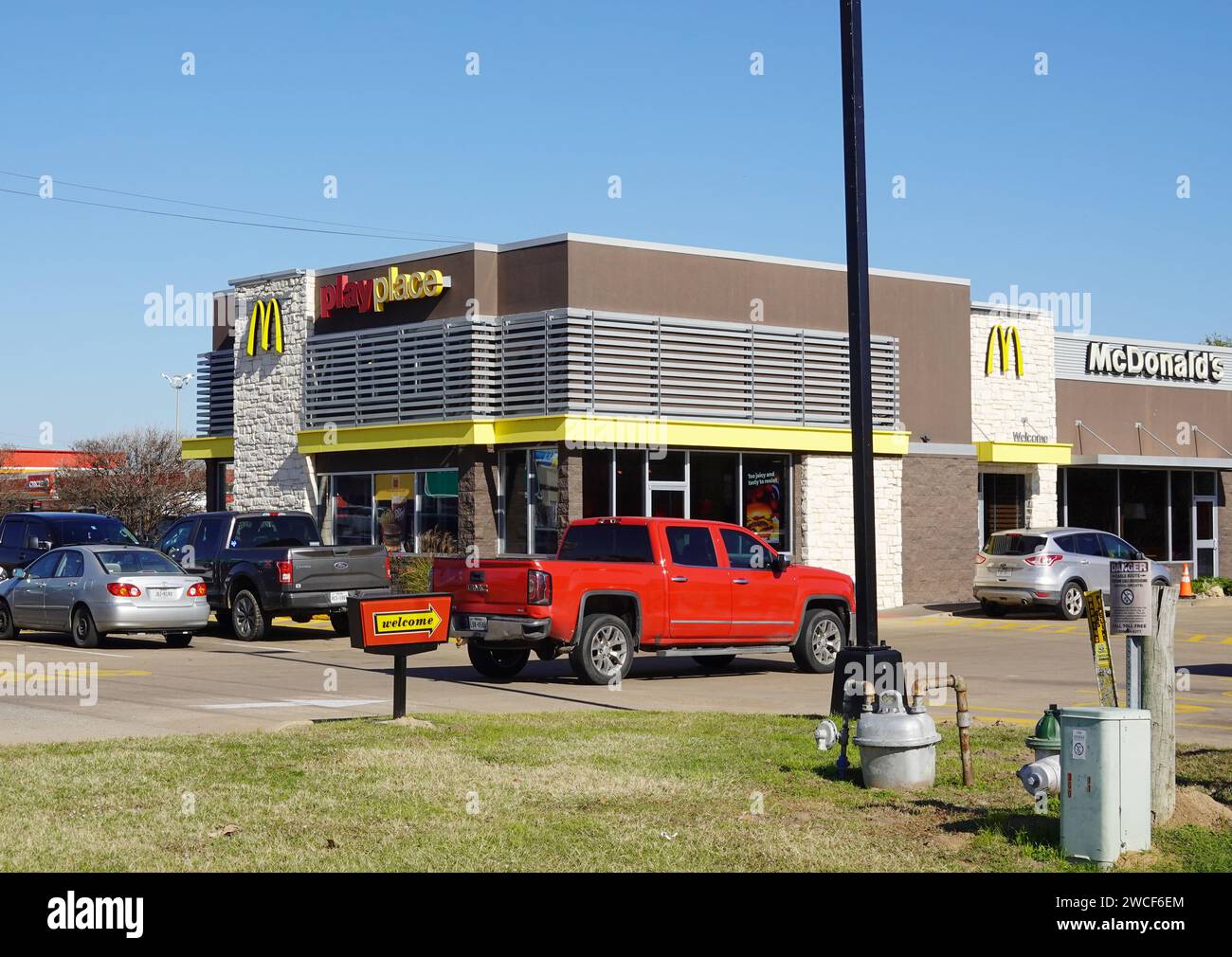Camionnette rouge vif entrant dans un parking McDonald's - novembre 2023 Banque D'Images